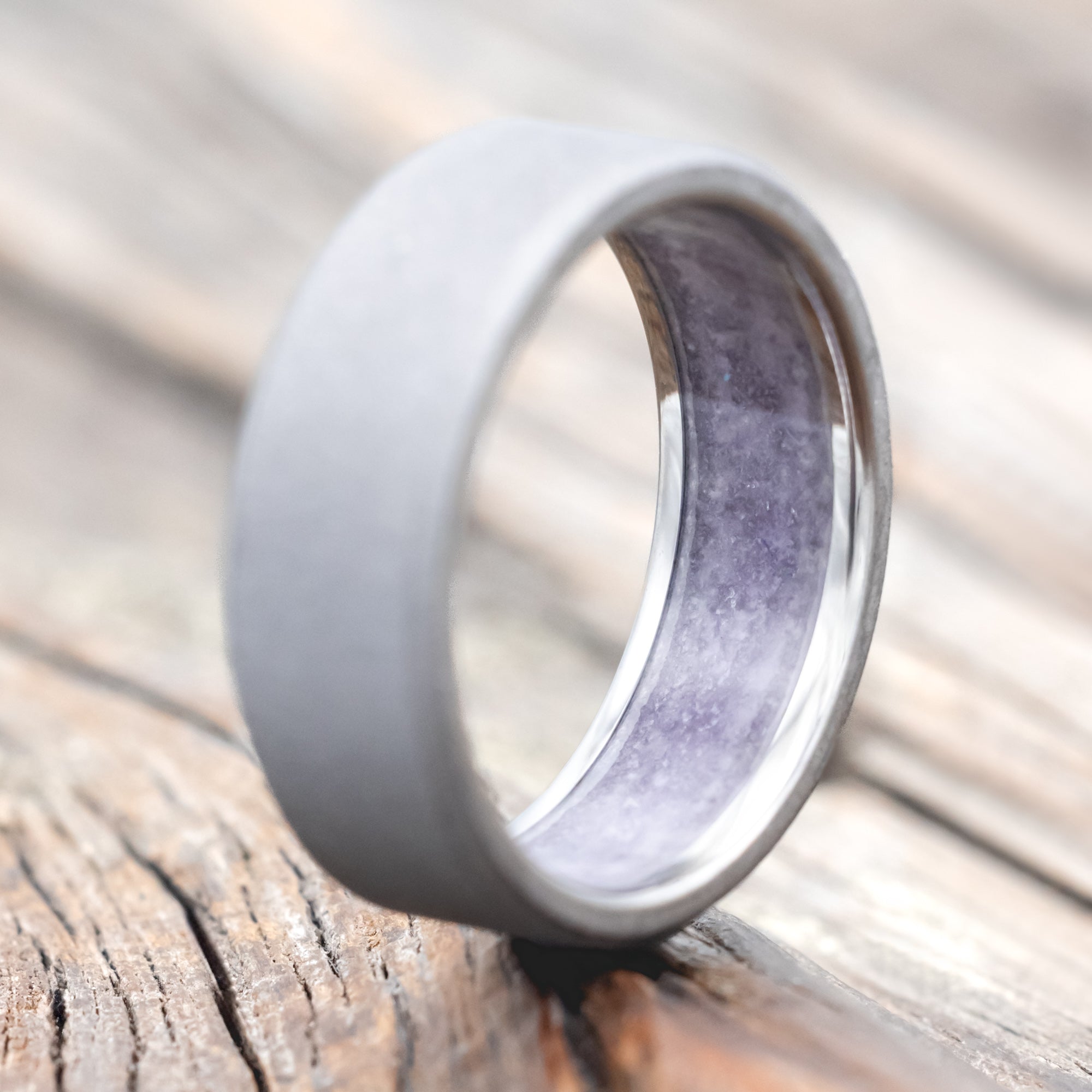 titanium ring with amethyst lining on a wooden surface against a blurred background