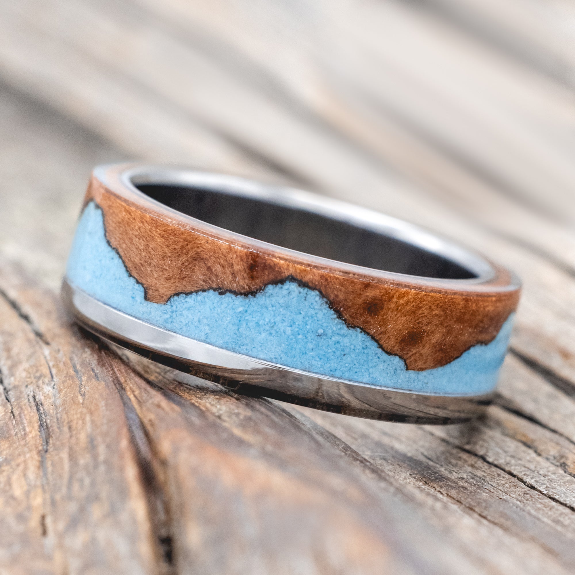 ring with redwood and turquoise inlay on a wooden surface