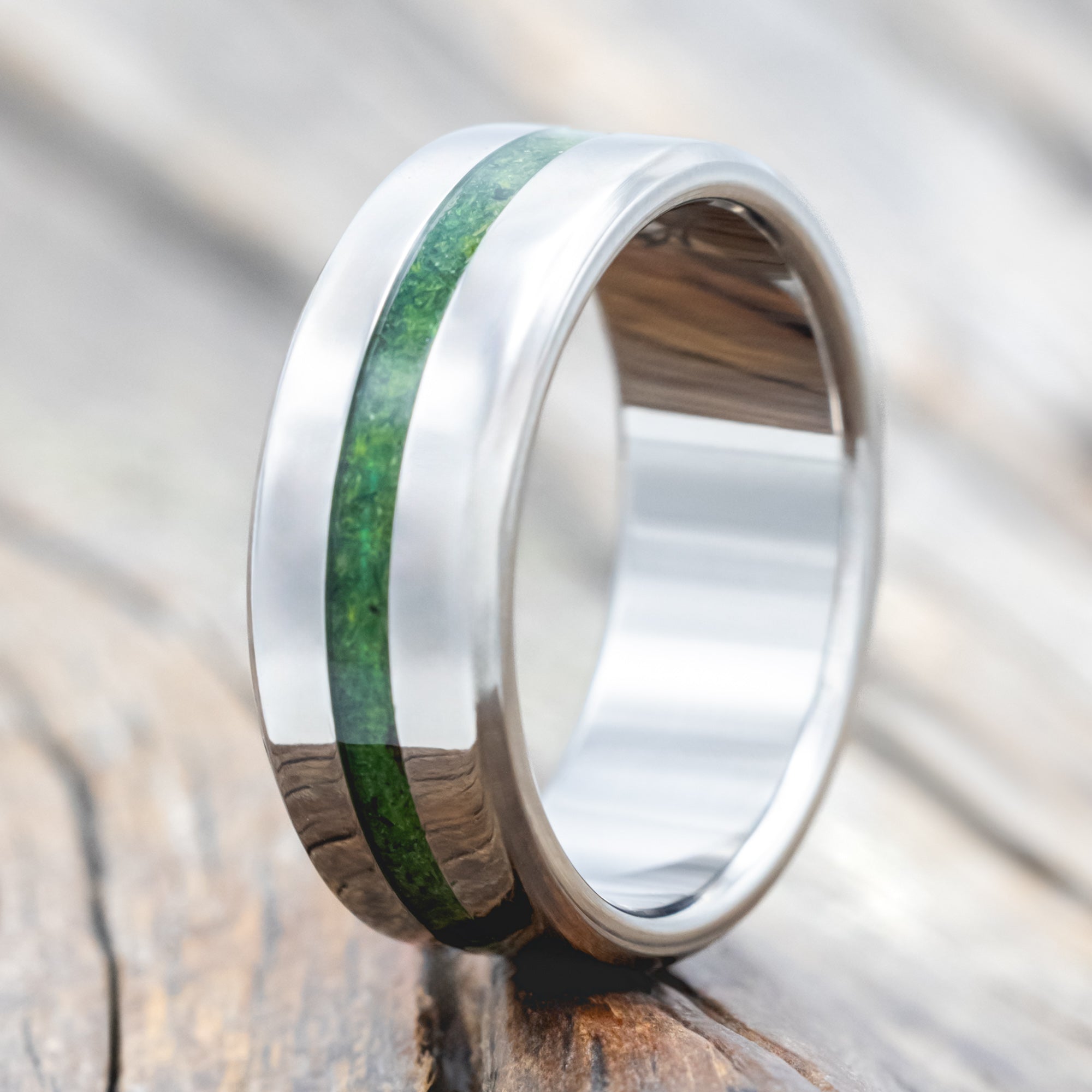 Titanium ring with moss inlay on a wooden surface