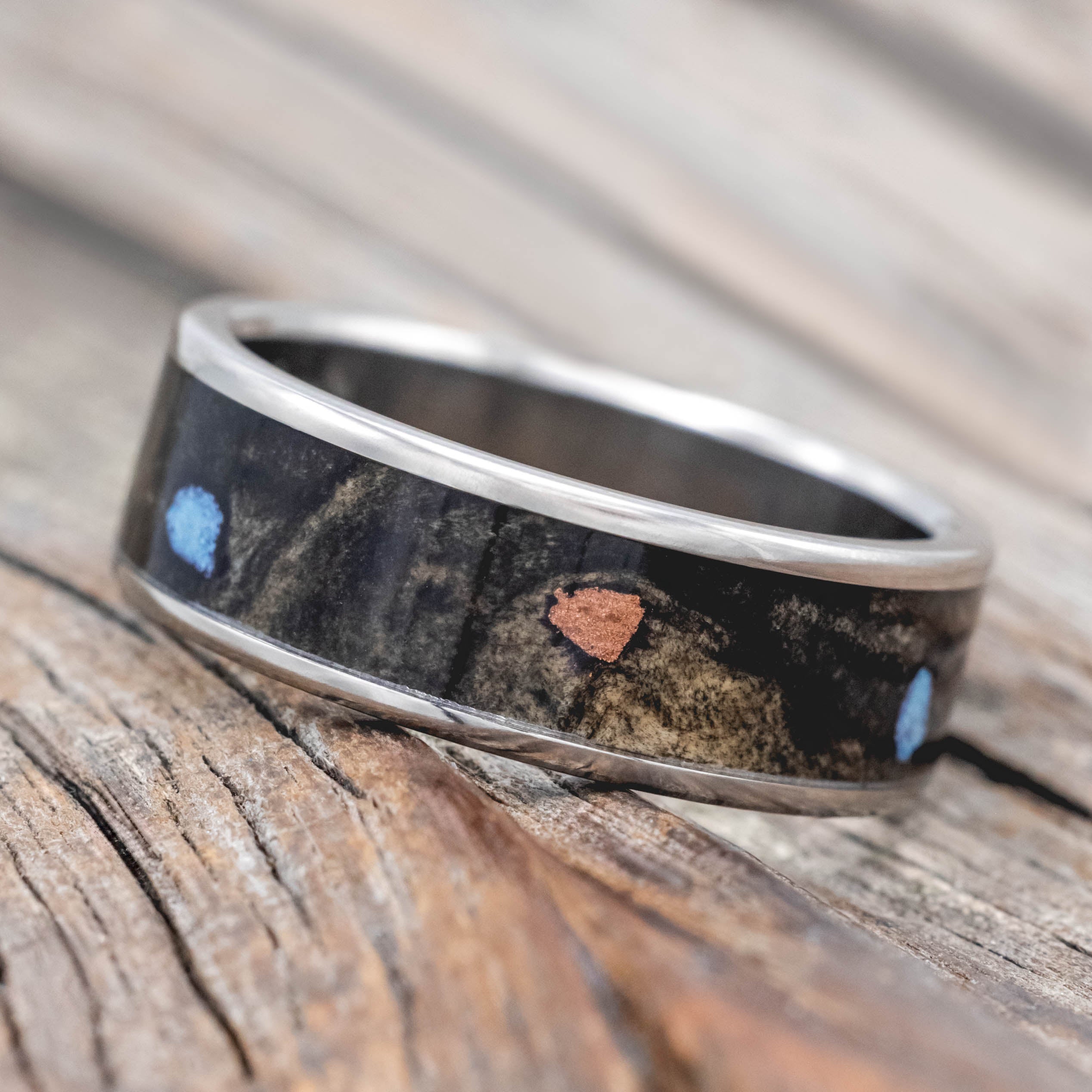 Wedding ring with buckeye burl with turquoise and powdered copper mix on a wooden surface