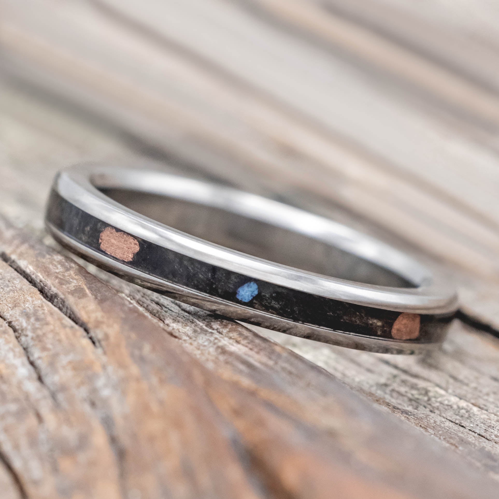 Wedding ring with buckeye burl with turquoise and powdered copper mix on a wooden surface