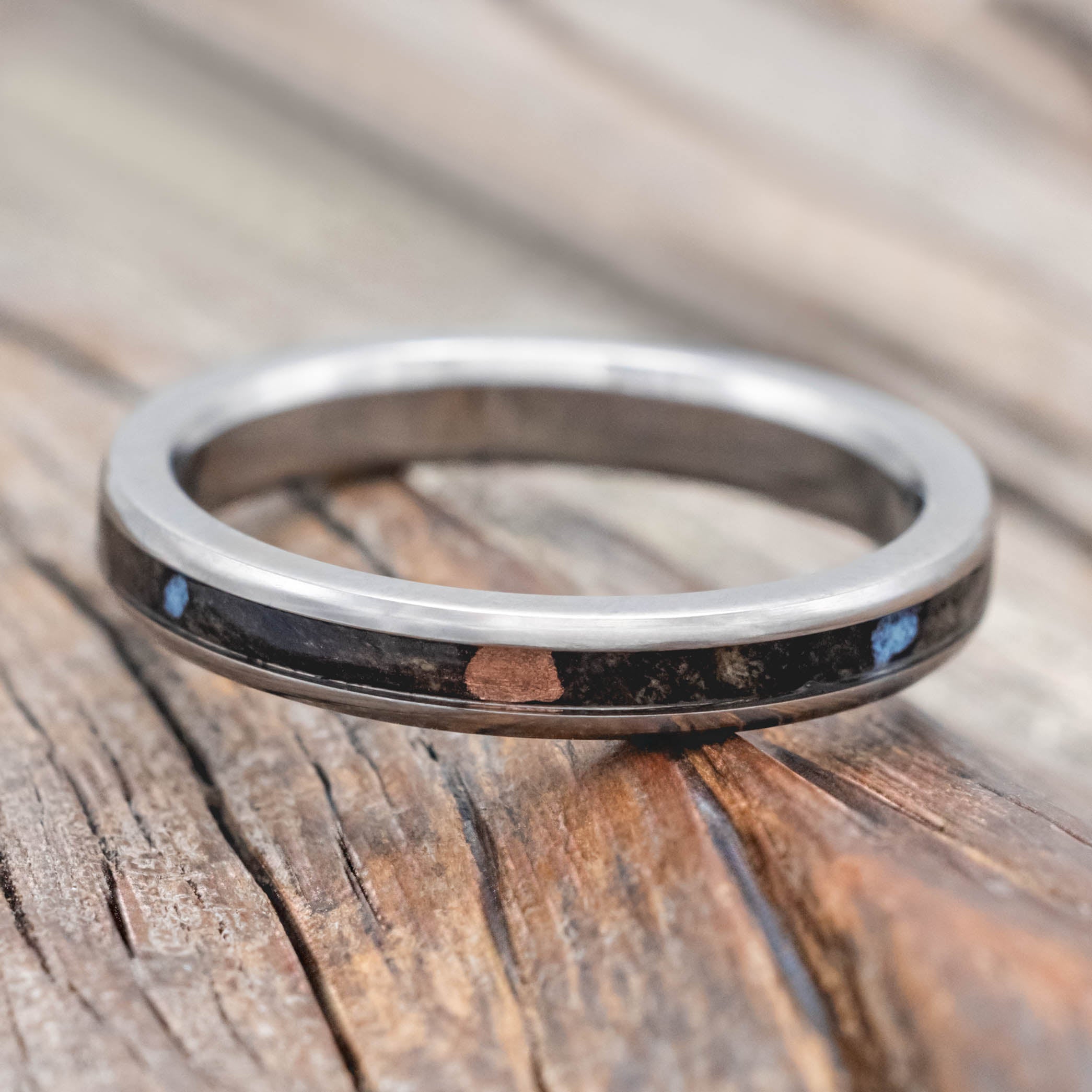 Wedding ring with buckeye burl with turquoise and powdered copper mix on a wooden surface