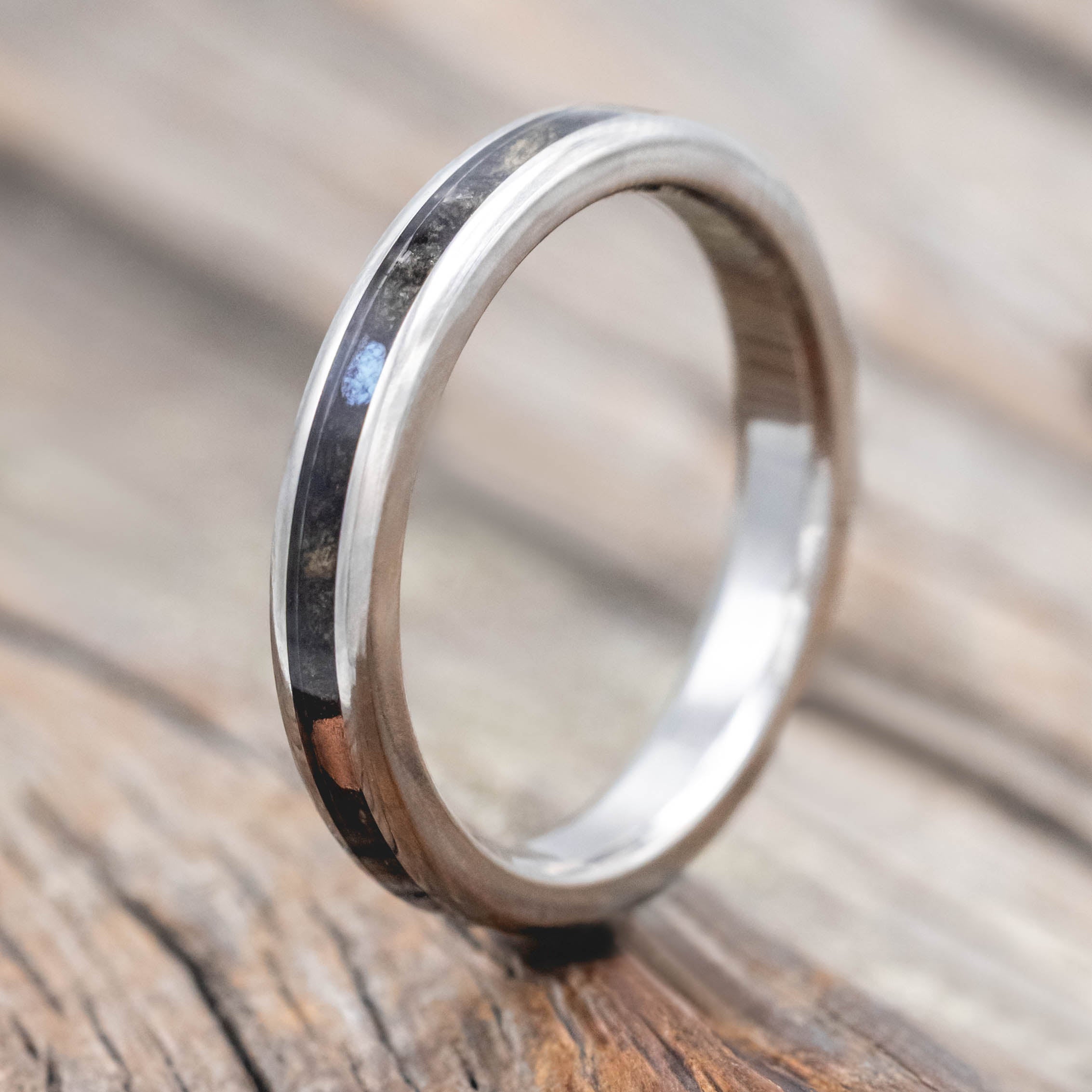 Wedding ring with buckeye burl with turquoise and powdered copper mix on a wooden surface