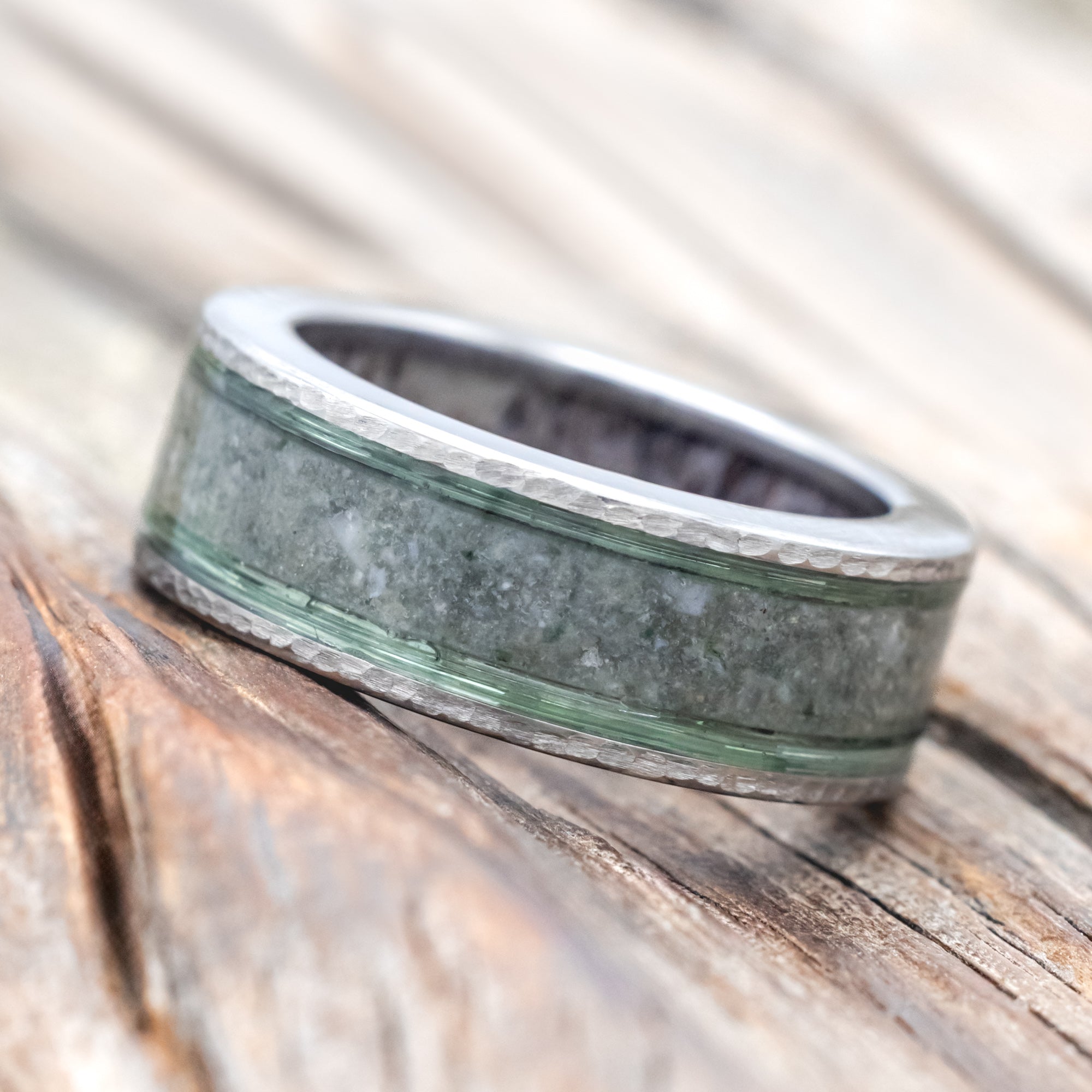 Ring with green and silver design on a wooden surface