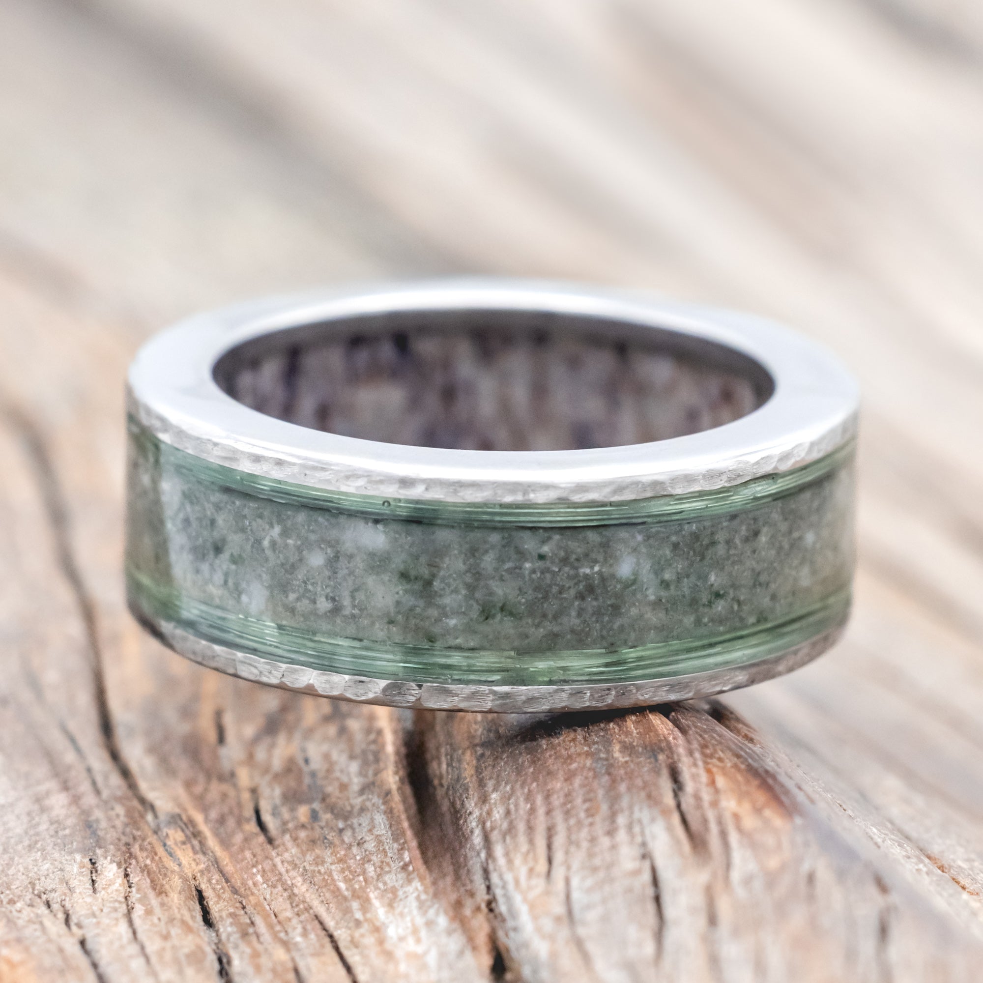 Ring with green and silver design on a wooden surface
