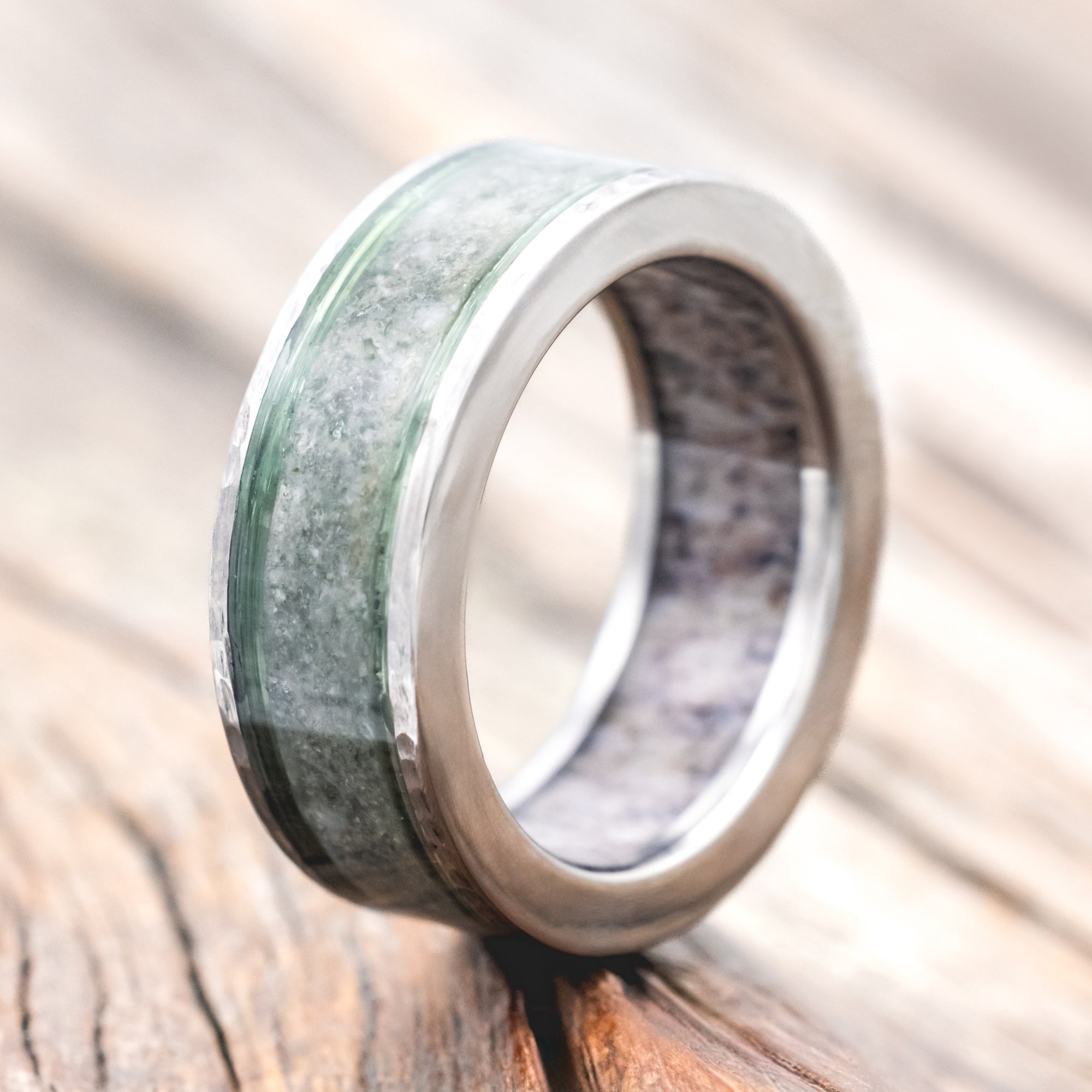 Ring with green and silver design on a wooden surface