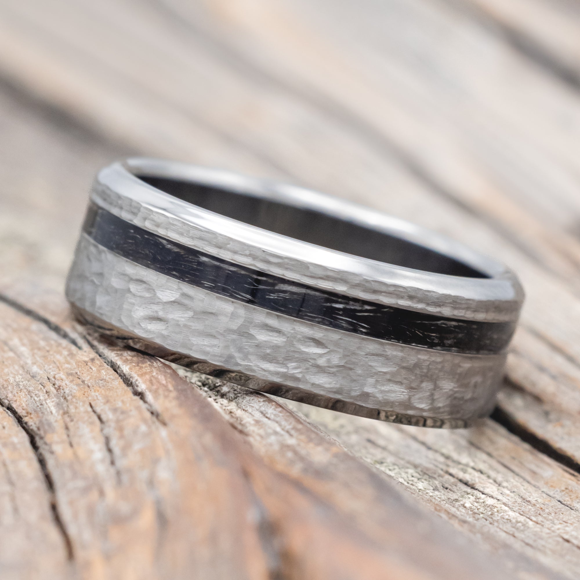 Titanium ring with duck feather inlay on a wooden surface