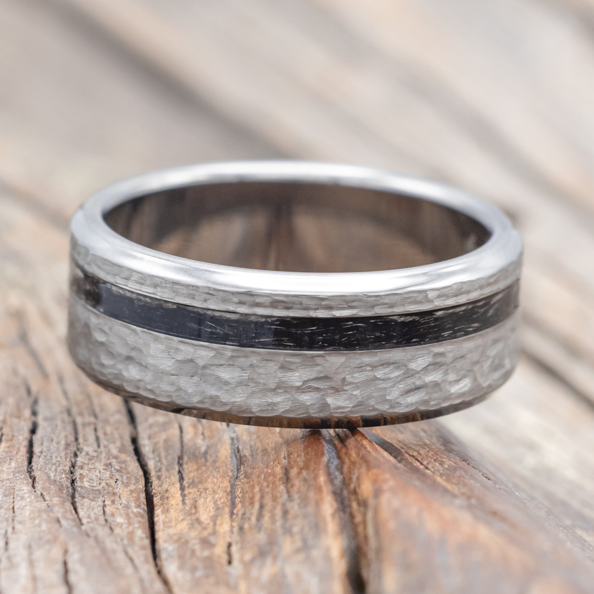 Titanium ring with duck feather inlay on a wooden surface