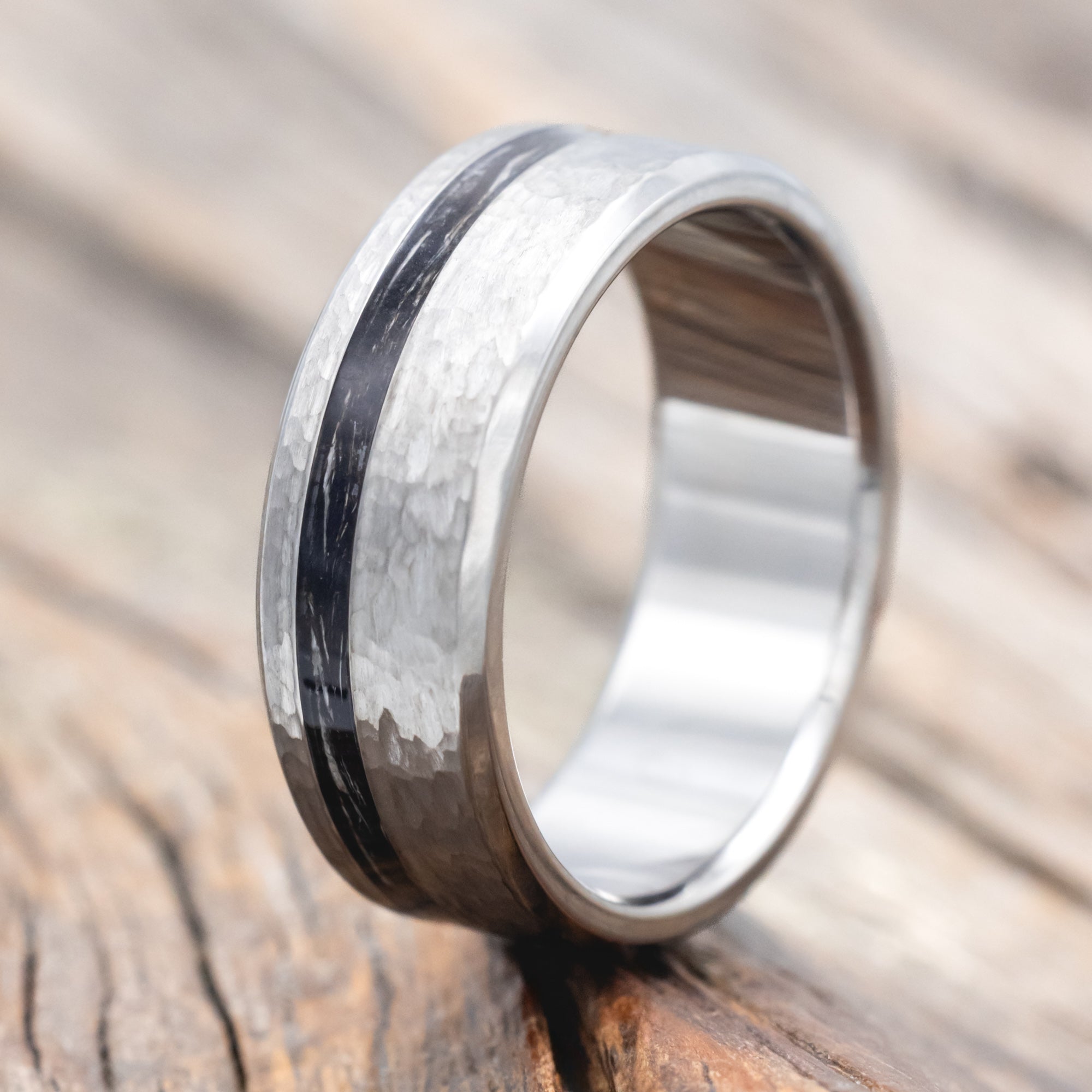 Titanium ring with duck feather inlay on a wooden surface