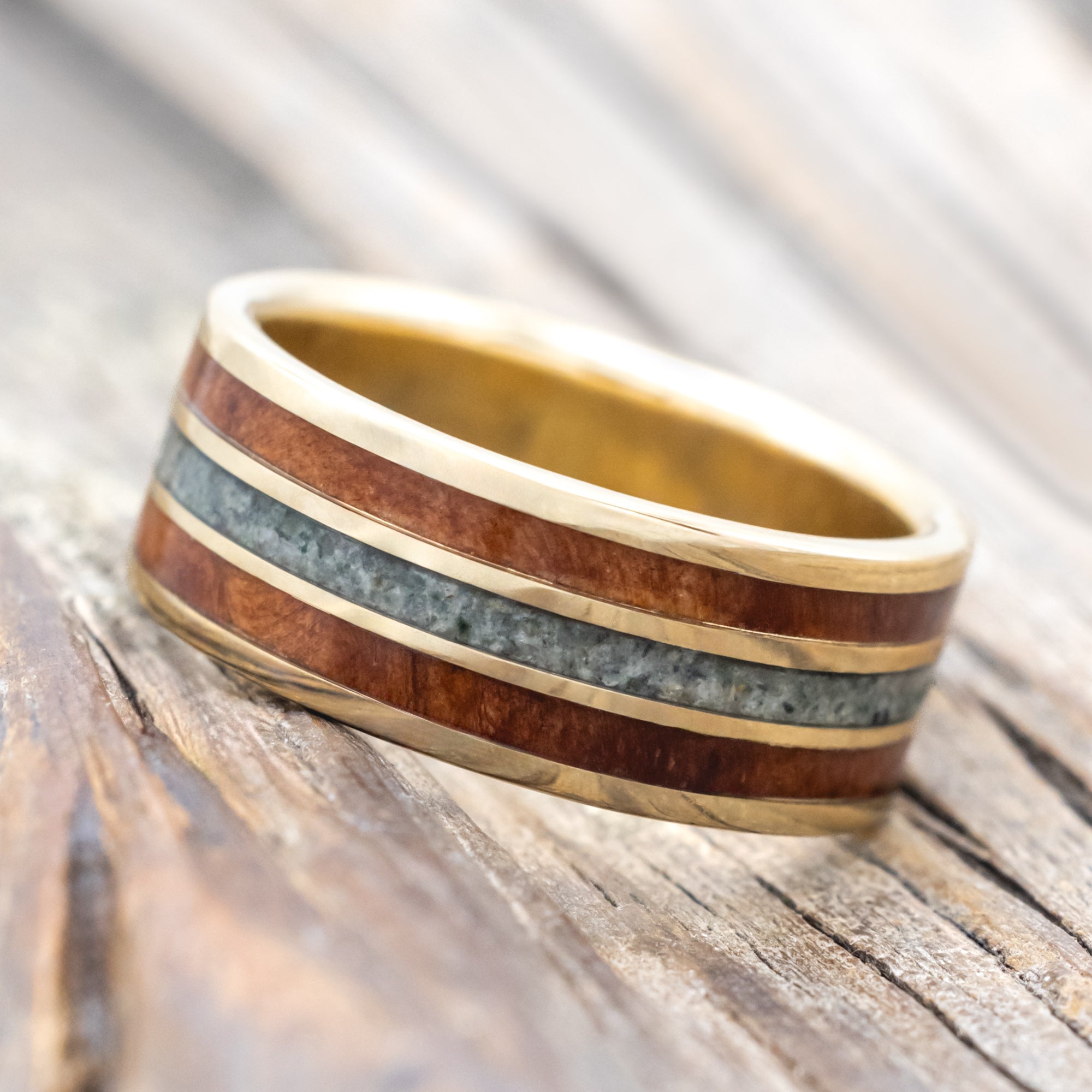 14K gold ring with koa wood and moss agate inlay on a wooden surface