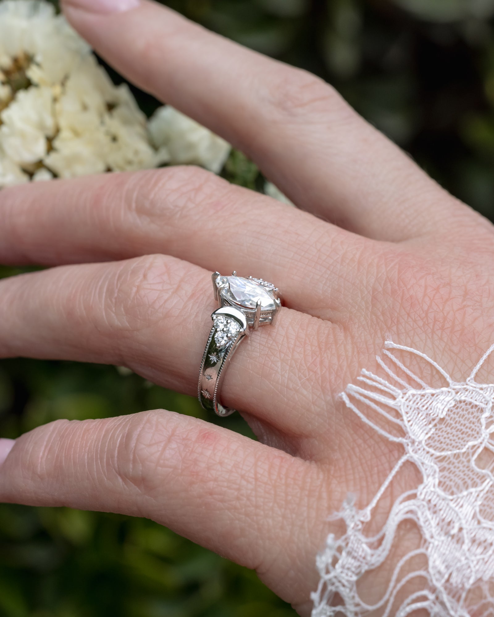 Close-up of a hand wearing a a moissanite ring with a blurred natural background