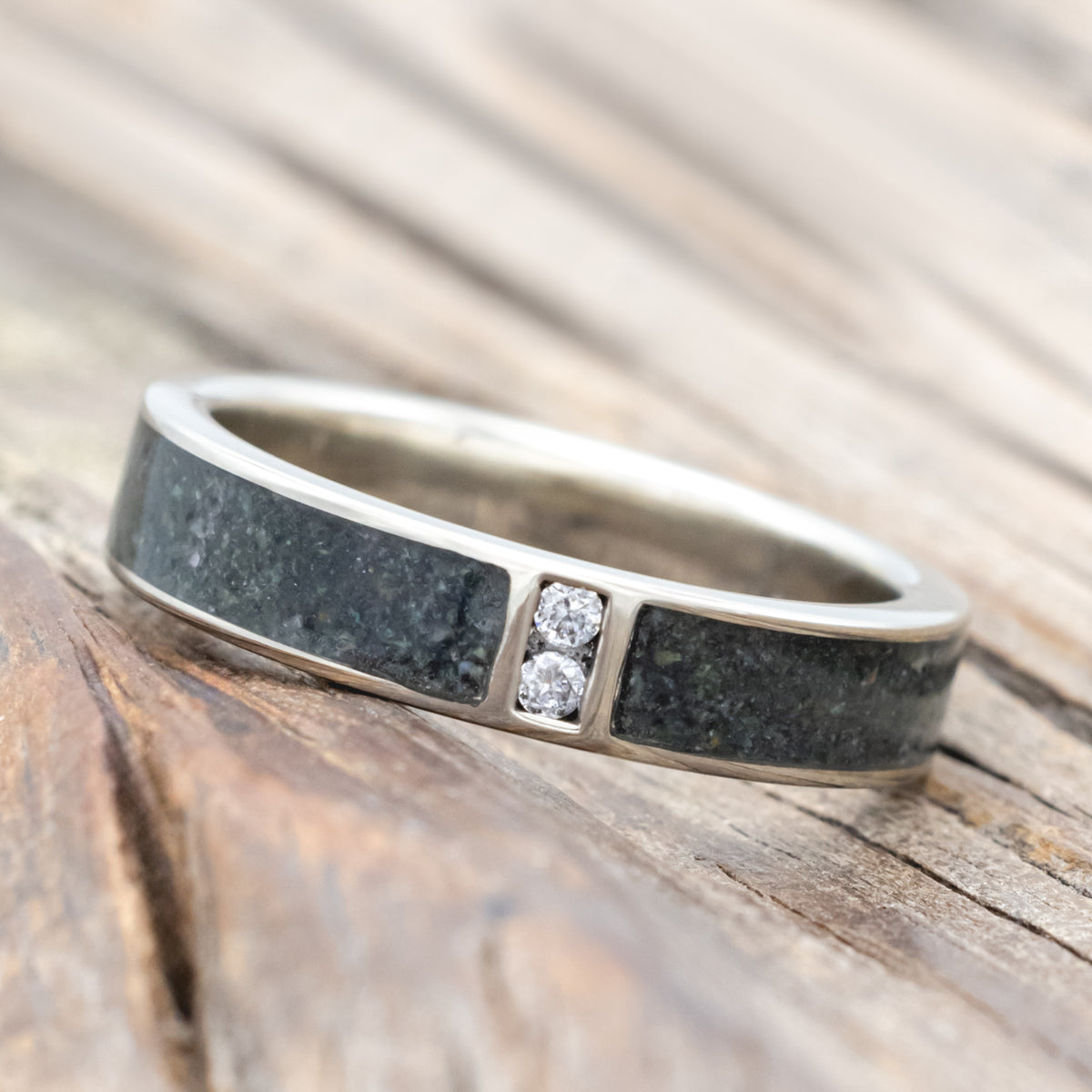 White gold ring with moss agate inlay and embedded diamonds on a wooden surface