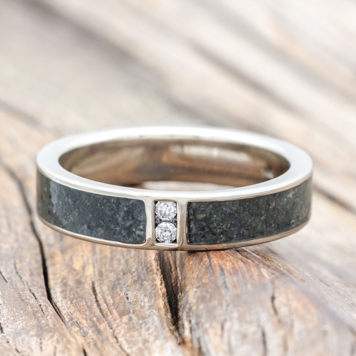 White gold ring with moss agate inlay and embedded diamonds on a wooden surface