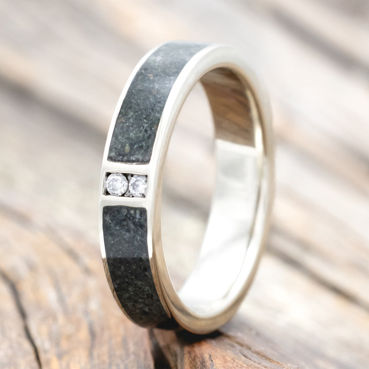 White gold ring with moss agate inlay and embedded diamonds on a wooden surface
