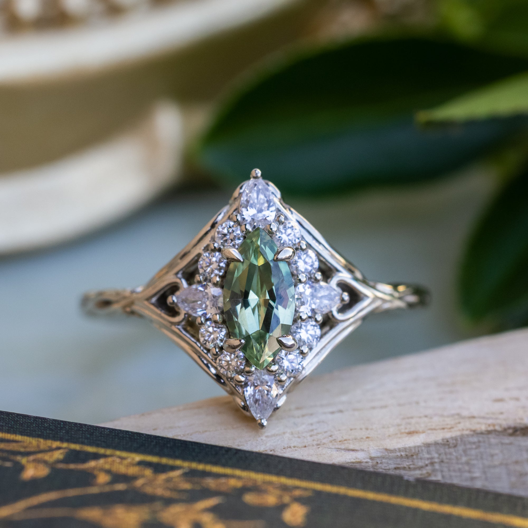 White gold ring with a green sapphire on a decorative surface