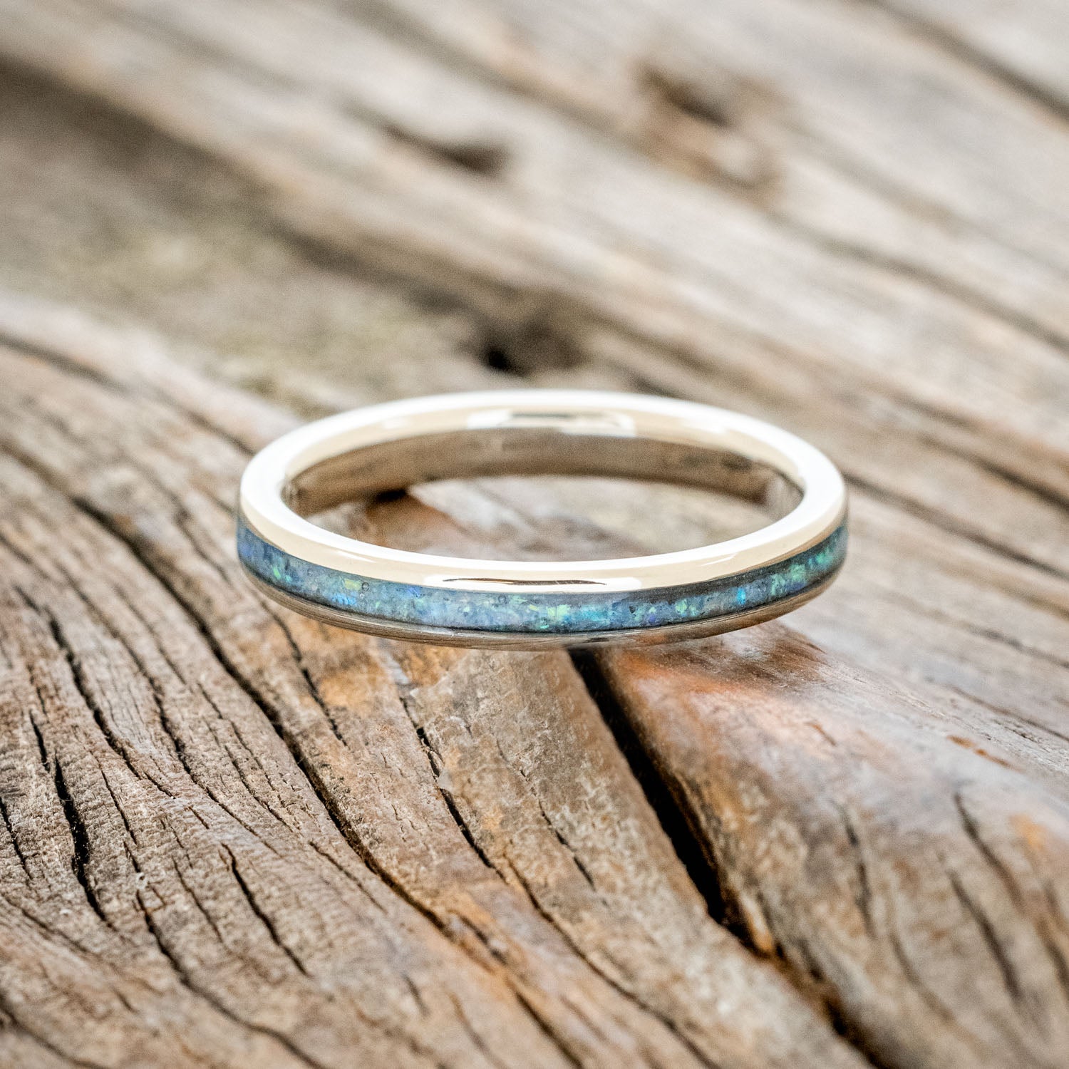 14K white gold ring with blue opal inlay on a wooden surface