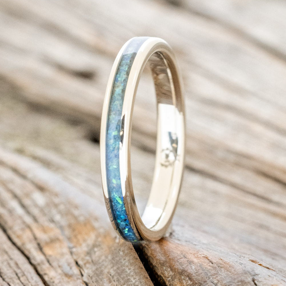 14K white gold ring with blue opal inlay on a wooden surface
