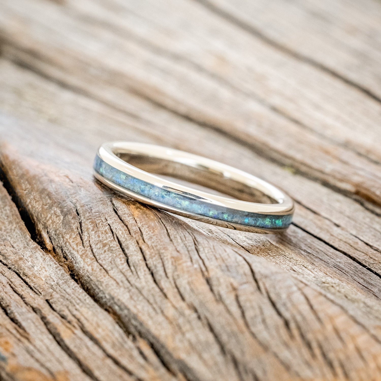 14K white gold ring with blue opal inlay on a wooden surface