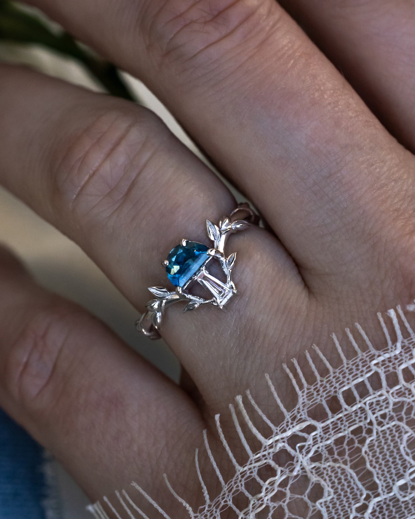 White gold mushroom ring with a blue sapphire on a person's finger