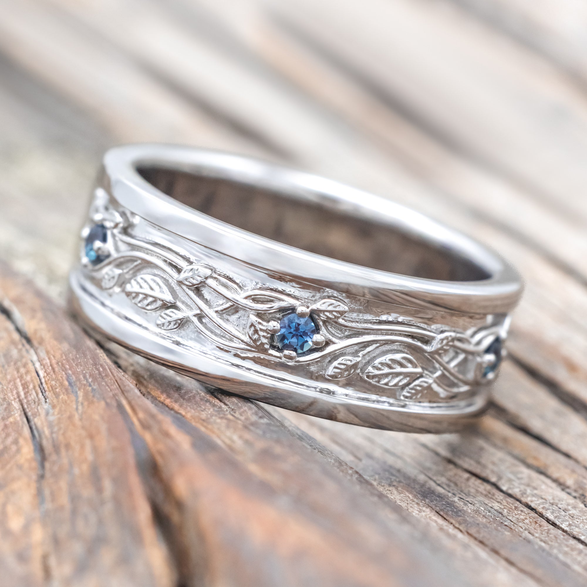 14K white gold ring with vines and lab Alexandrite accents on a wooden surface