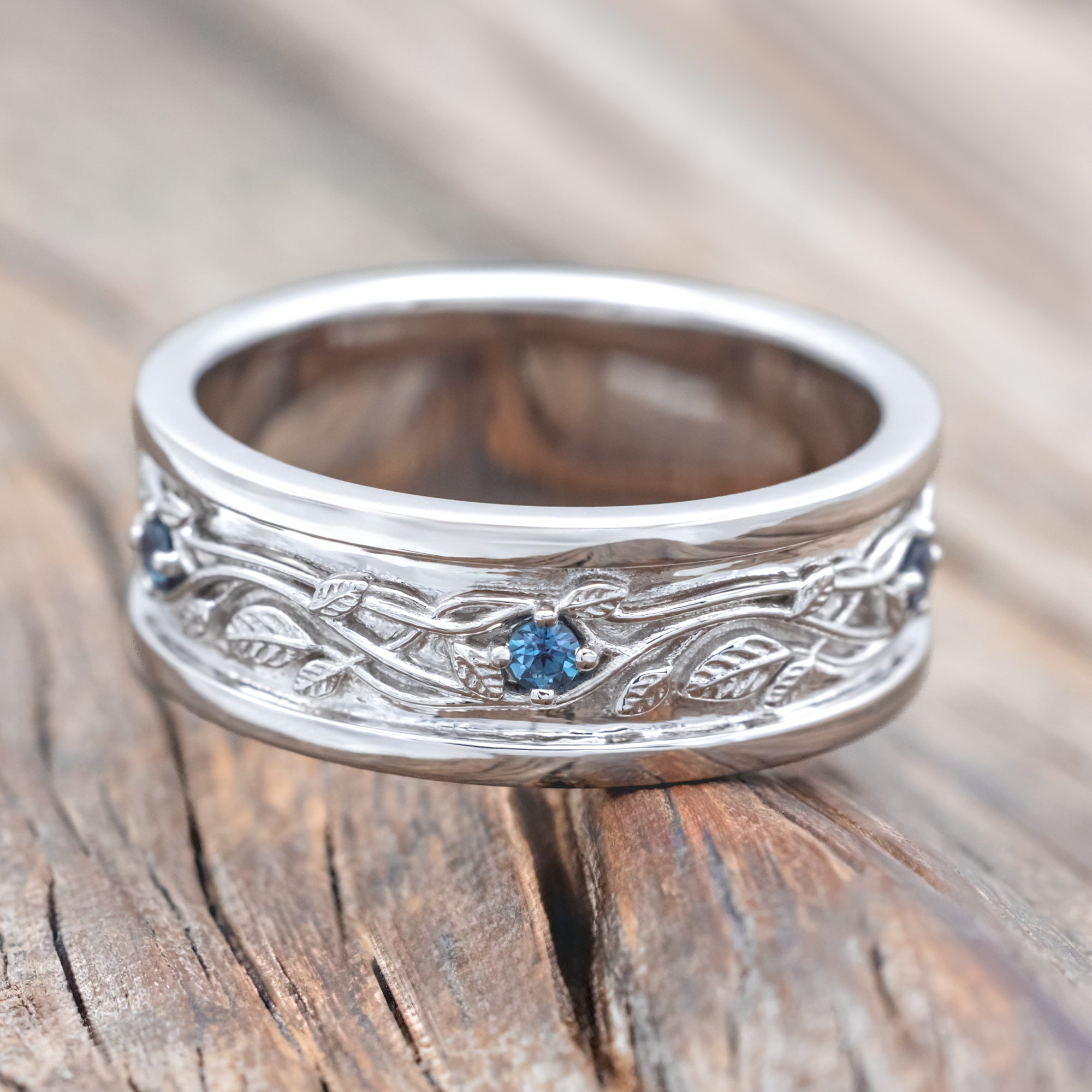 14K white gold ring with vines and lab Alexandrite accents on a wooden surface