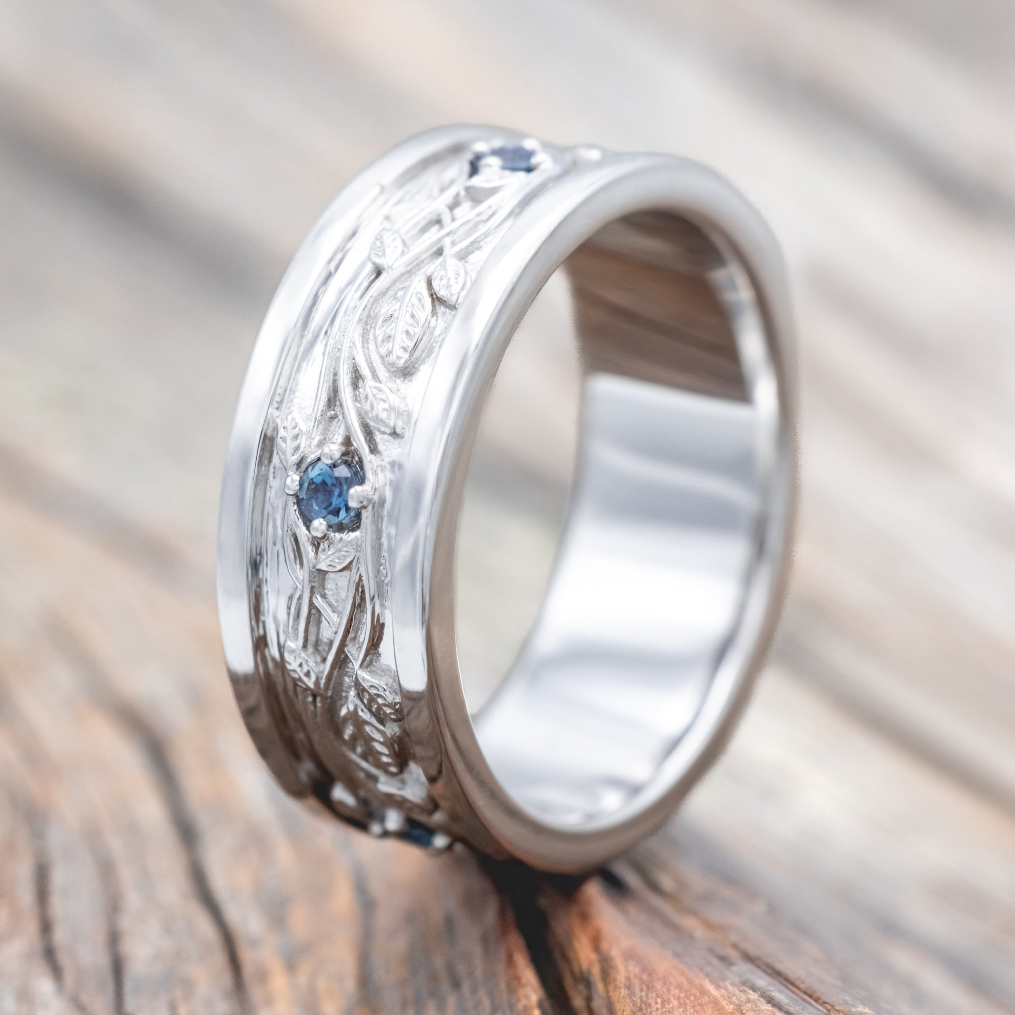 14K white gold ring with vines and lab Alexandrite accents on a wooden surface