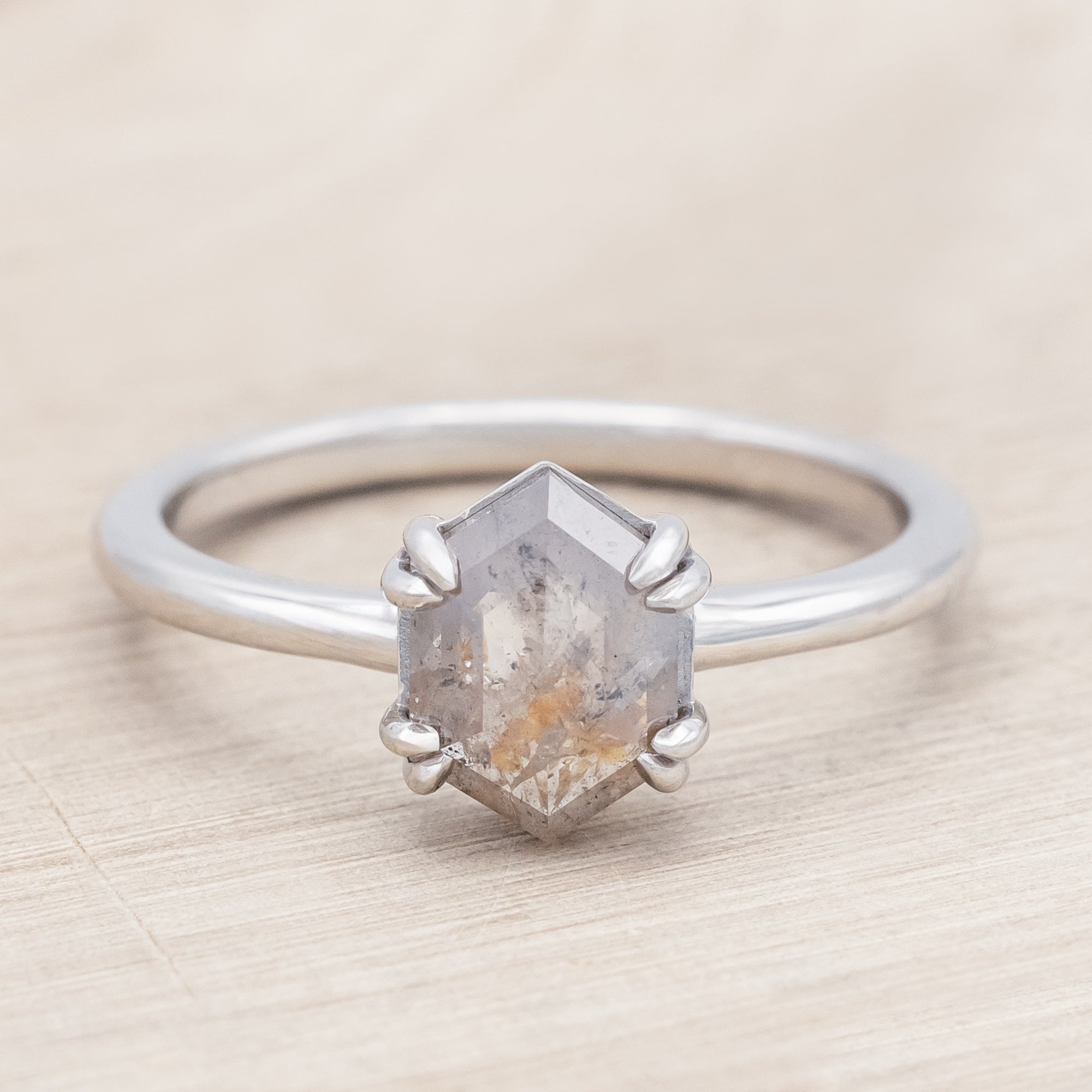 White gold ring with a hexagon salt & pepper diamond on a beige background
