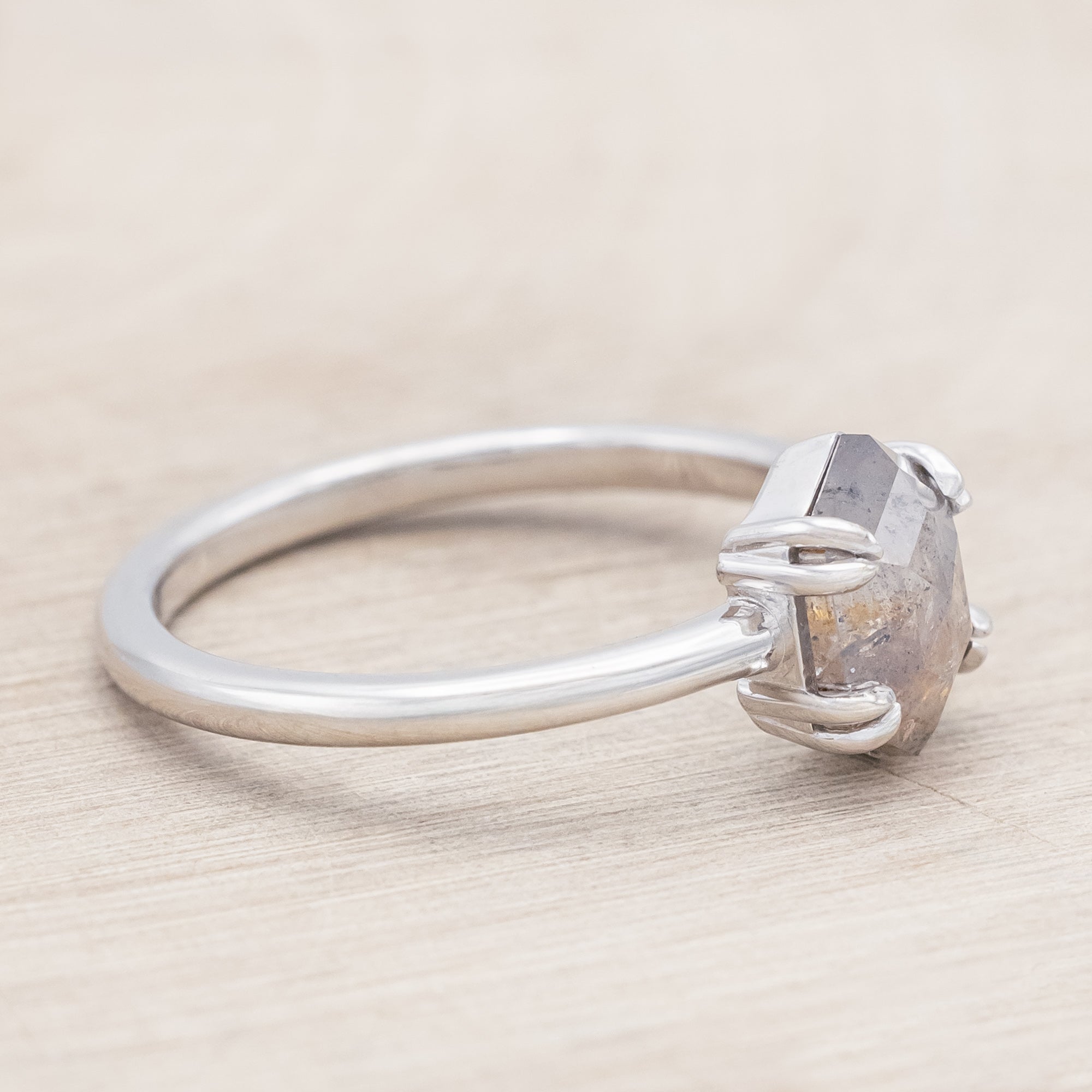 White gold ring with a hexagon salt & pepper diamond on a beige background