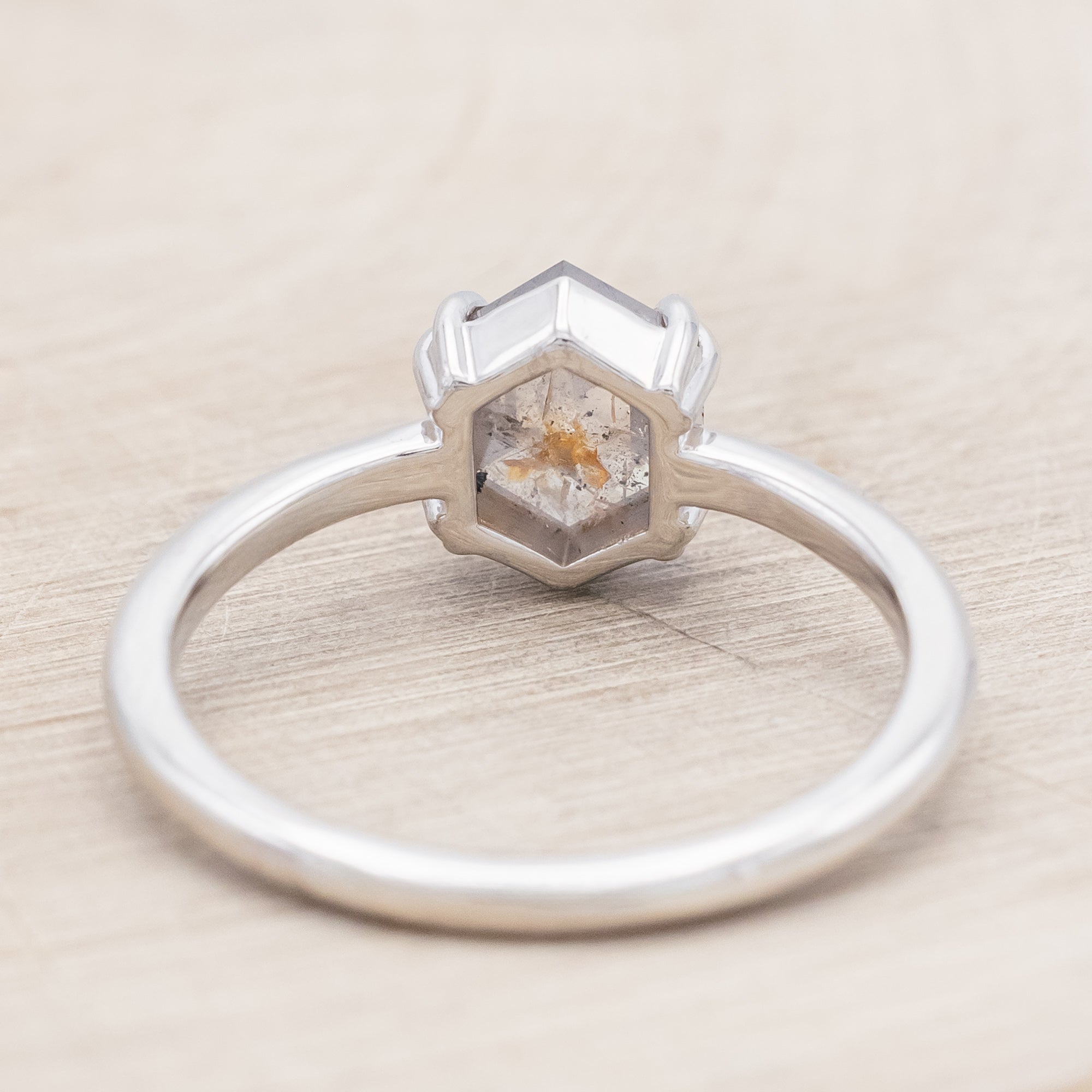 White gold ring with a hexagon salt & pepper diamond on a beige background