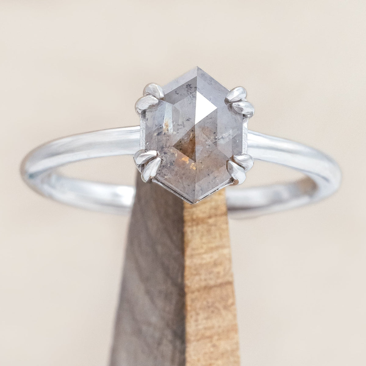 White gold ring with a hexagon salt & pepper diamond on a beige background