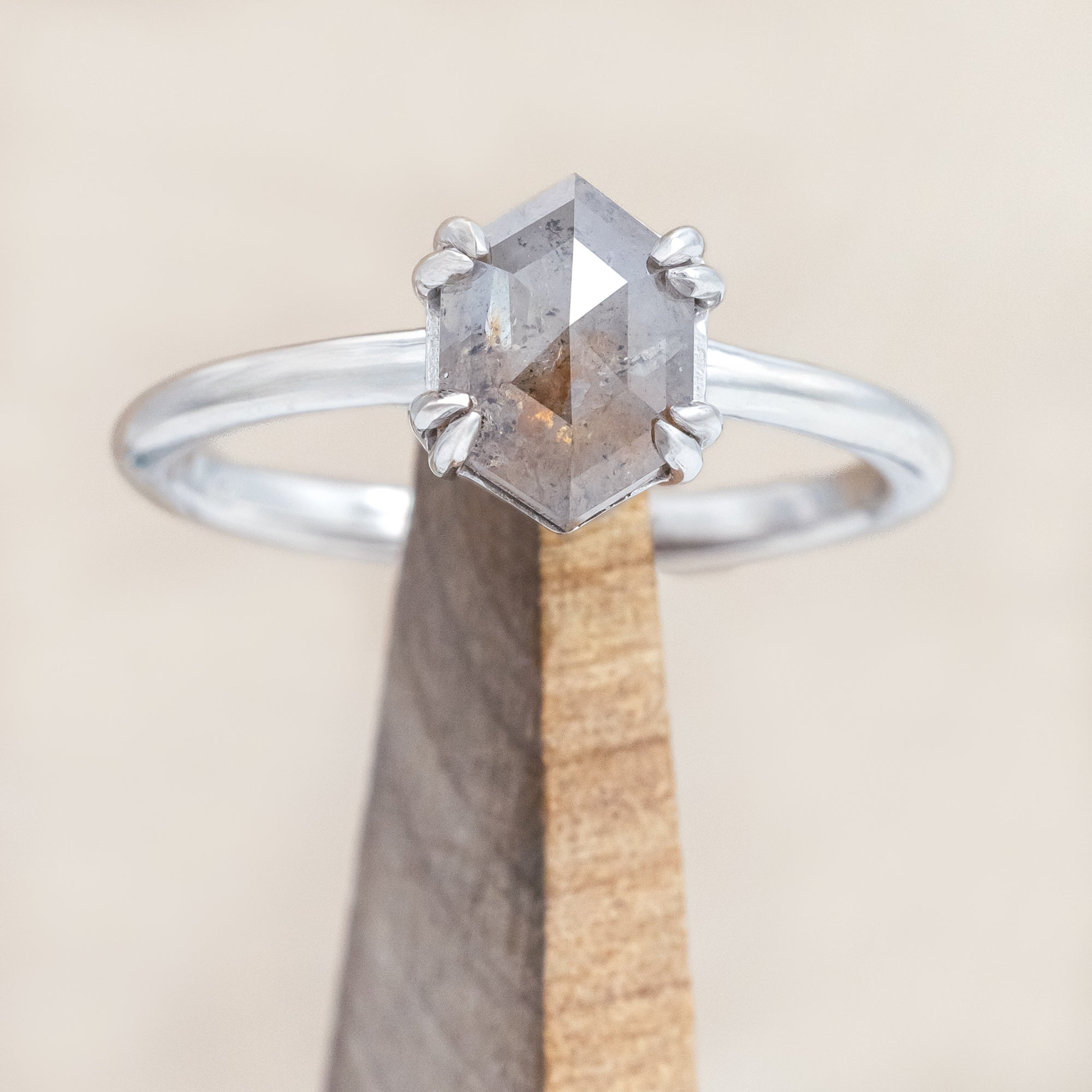 White gold ring with a hexagon salt & pepper diamond on a beige background