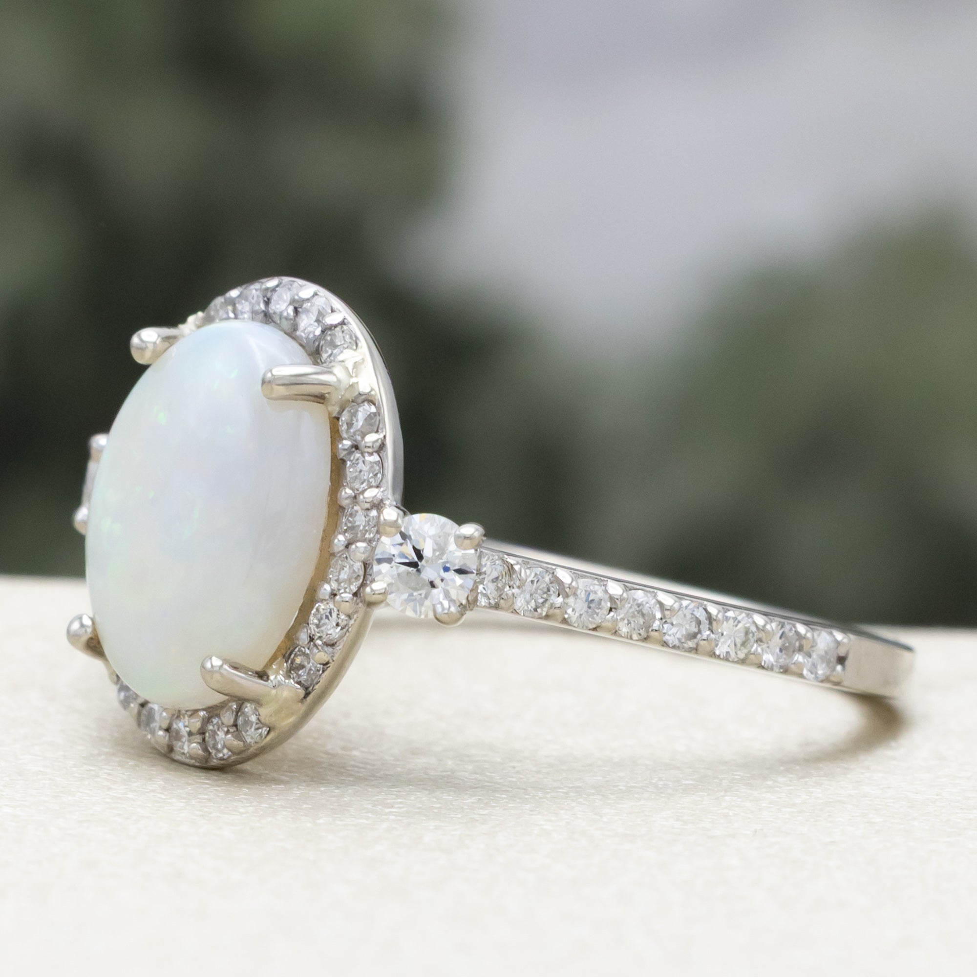White gold ring with an oval opal stone and diamond accents on a neutral background