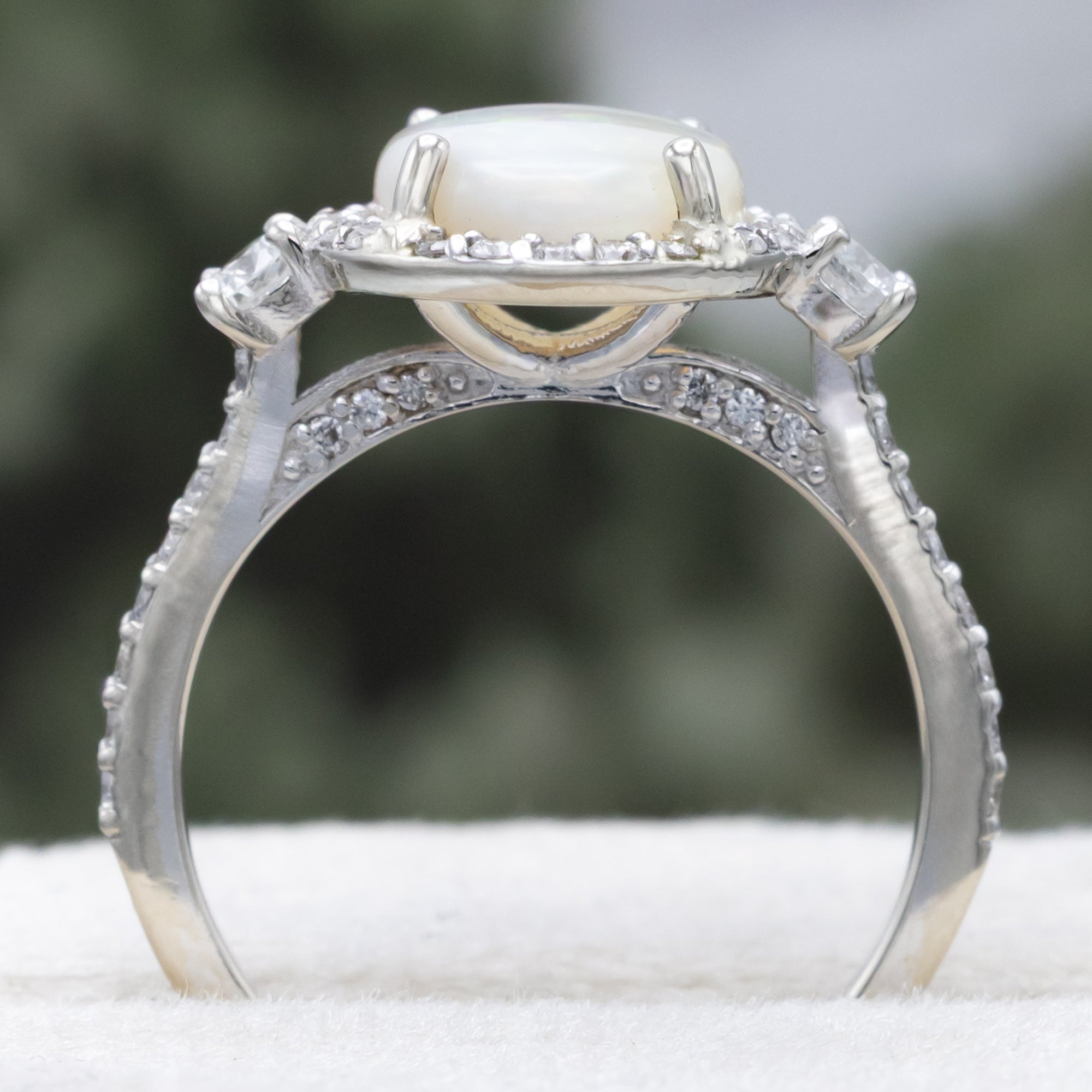 White gold ring with an oval opal stone and diamond accents on a neutral background