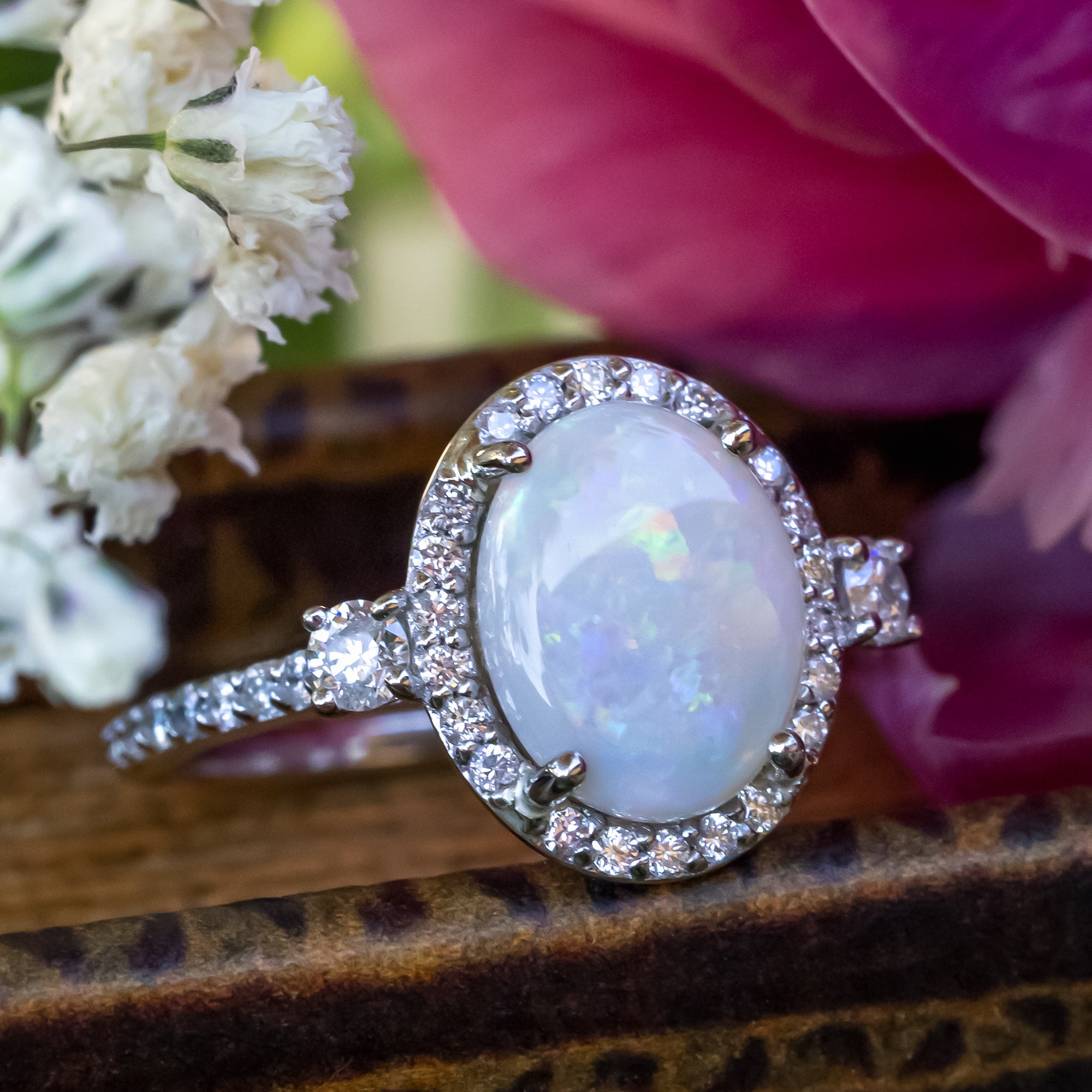 Ring with a large opal centerstone and diamond accents on a floral background