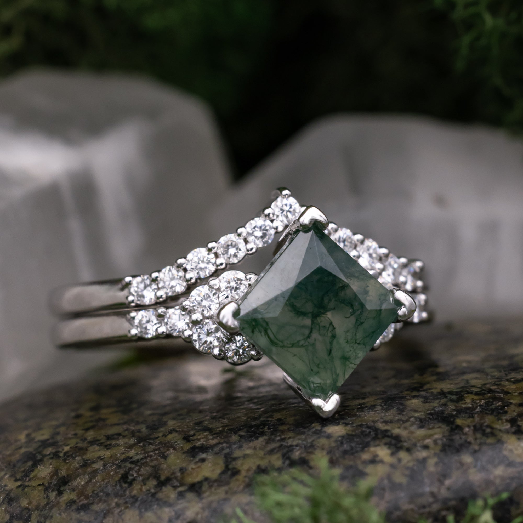 White gold ring with a moss agate centerstone on a stone surface