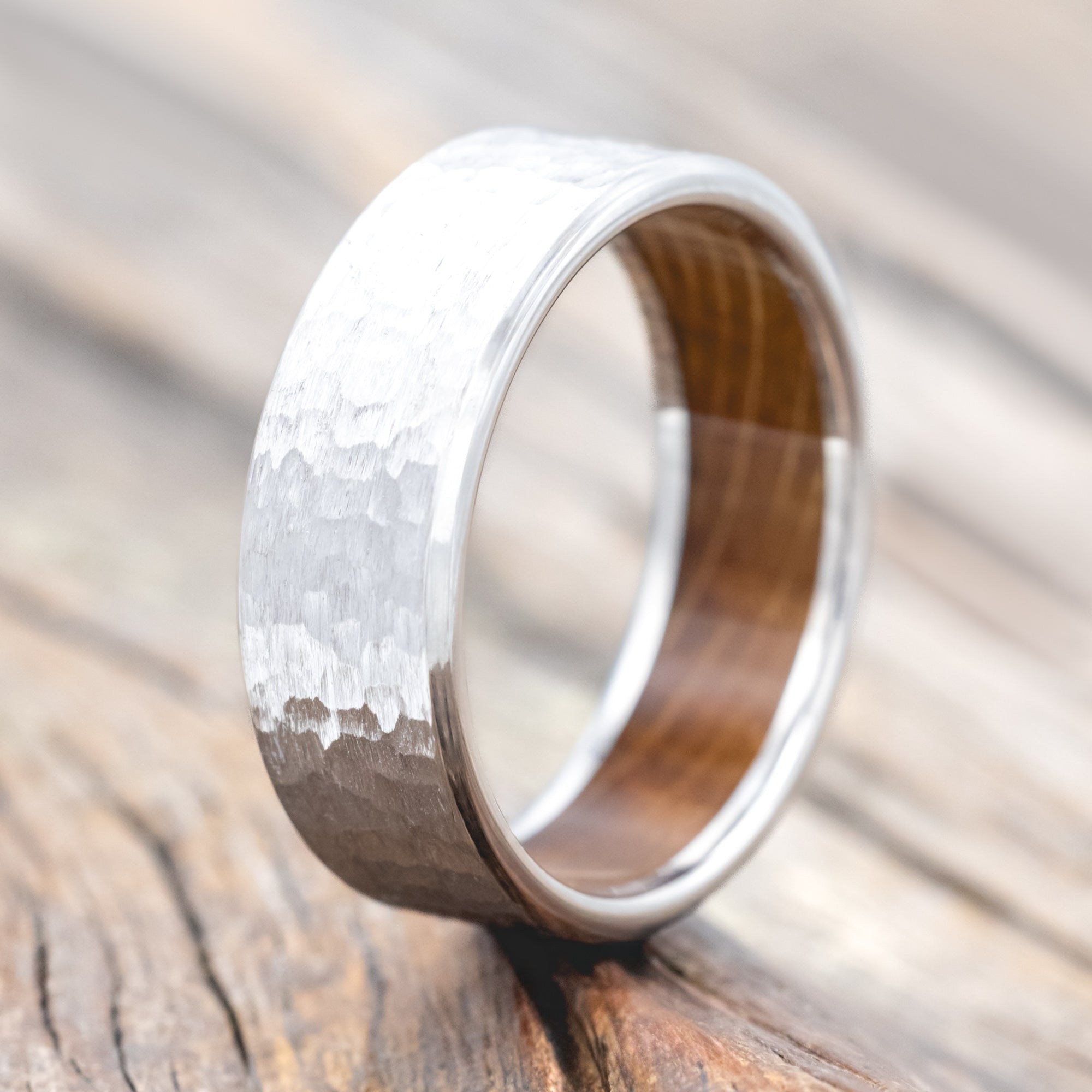 Hammered white gold ring with whiskey barrel oak lining on a wooden surface