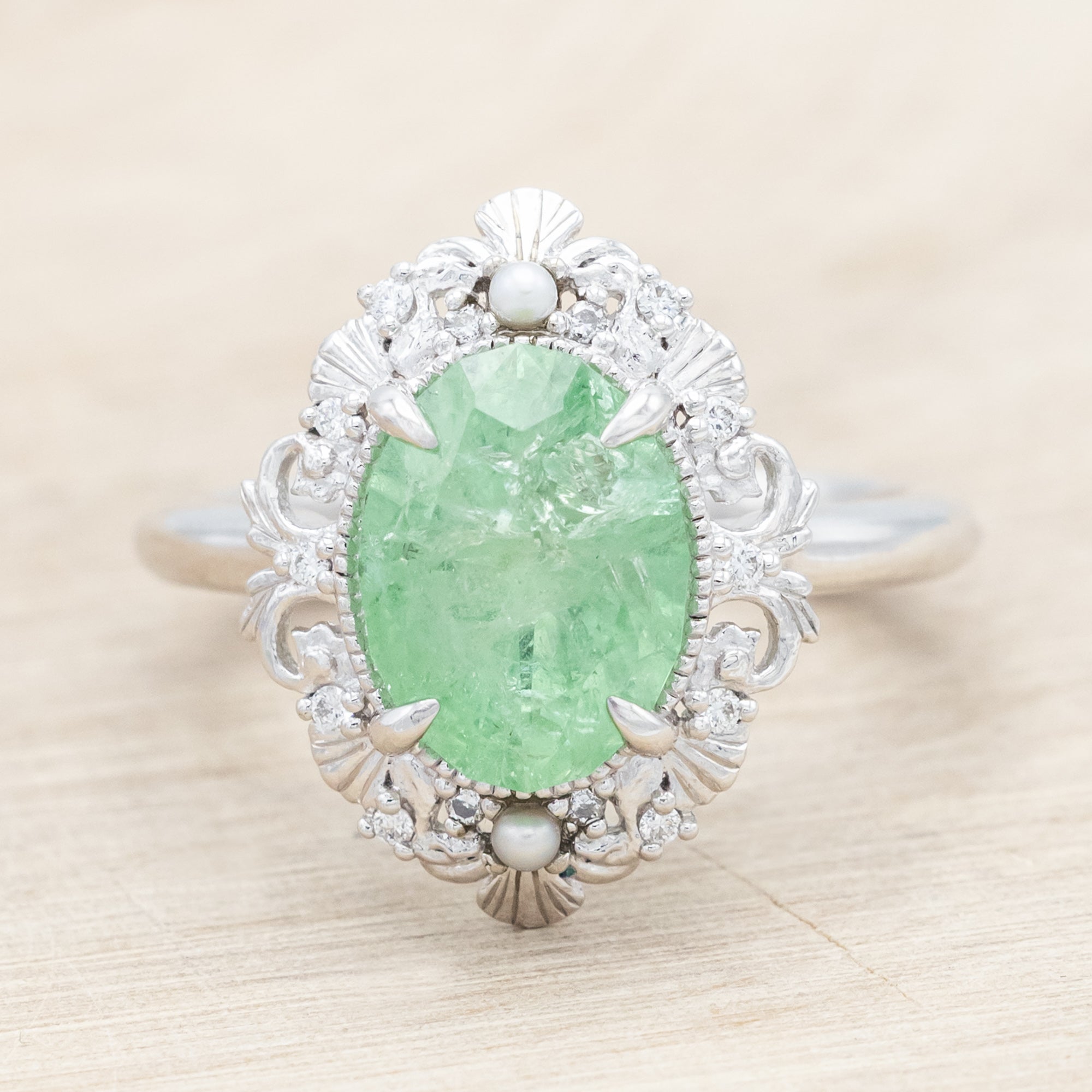 14K white gold ring with a green garnet on a light wooden background
