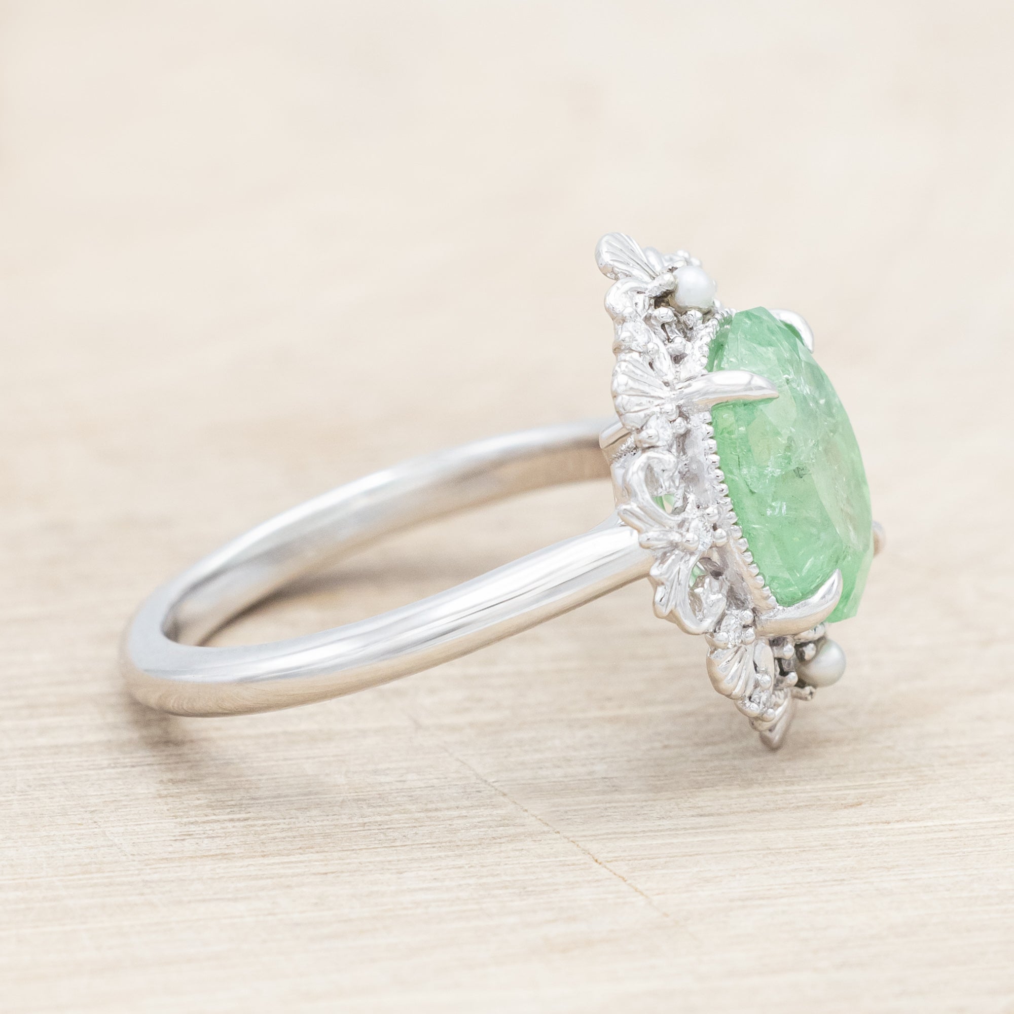 14K white gold ring with a green garnet on a light wooden background