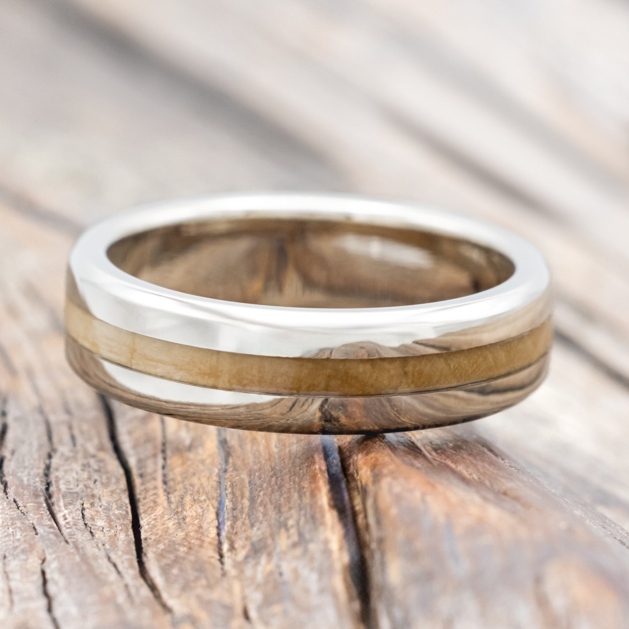 14K white gold and fig wood ring on a wooden surface with a blurred background