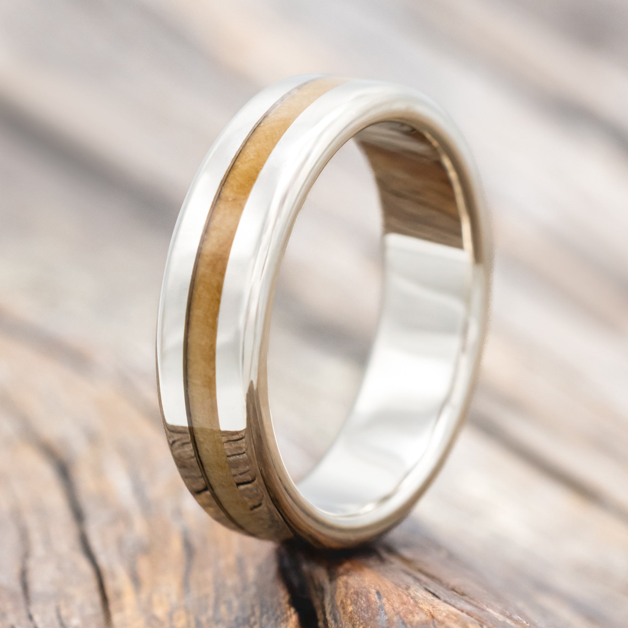 14K white gold and fig wood ring on a wooden surface with a blurred background