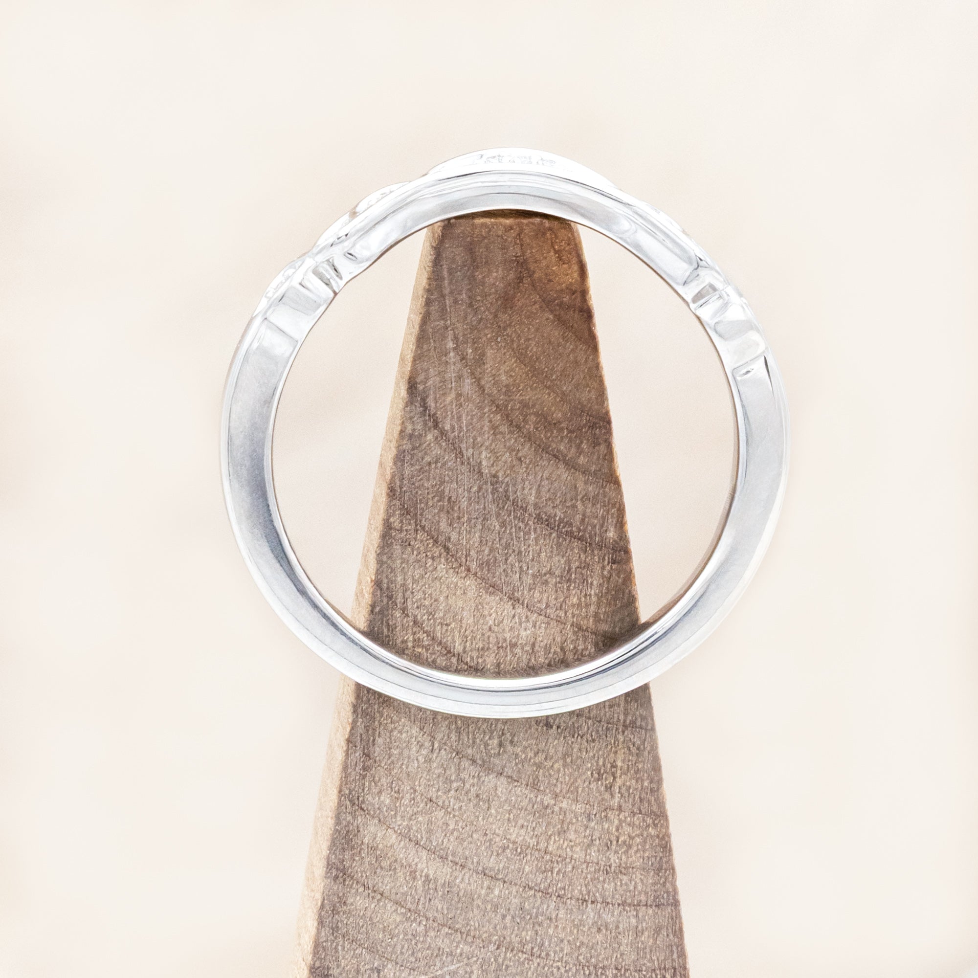14K white gold ring with diamond accents on a wooden stand
