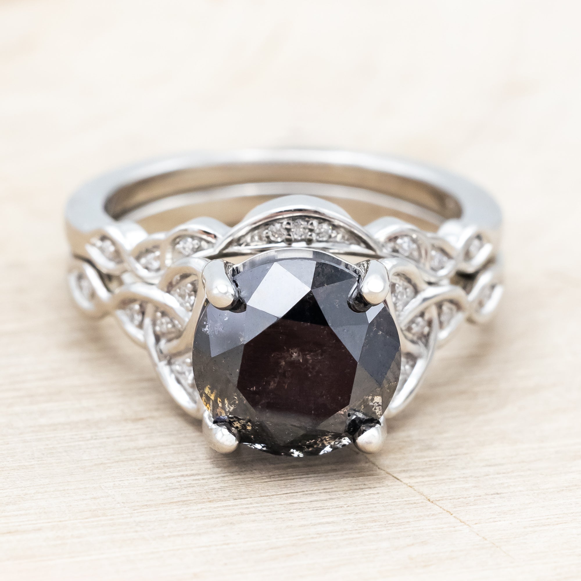14K white gold ring with a salt & pepper diamond on a wooden surface