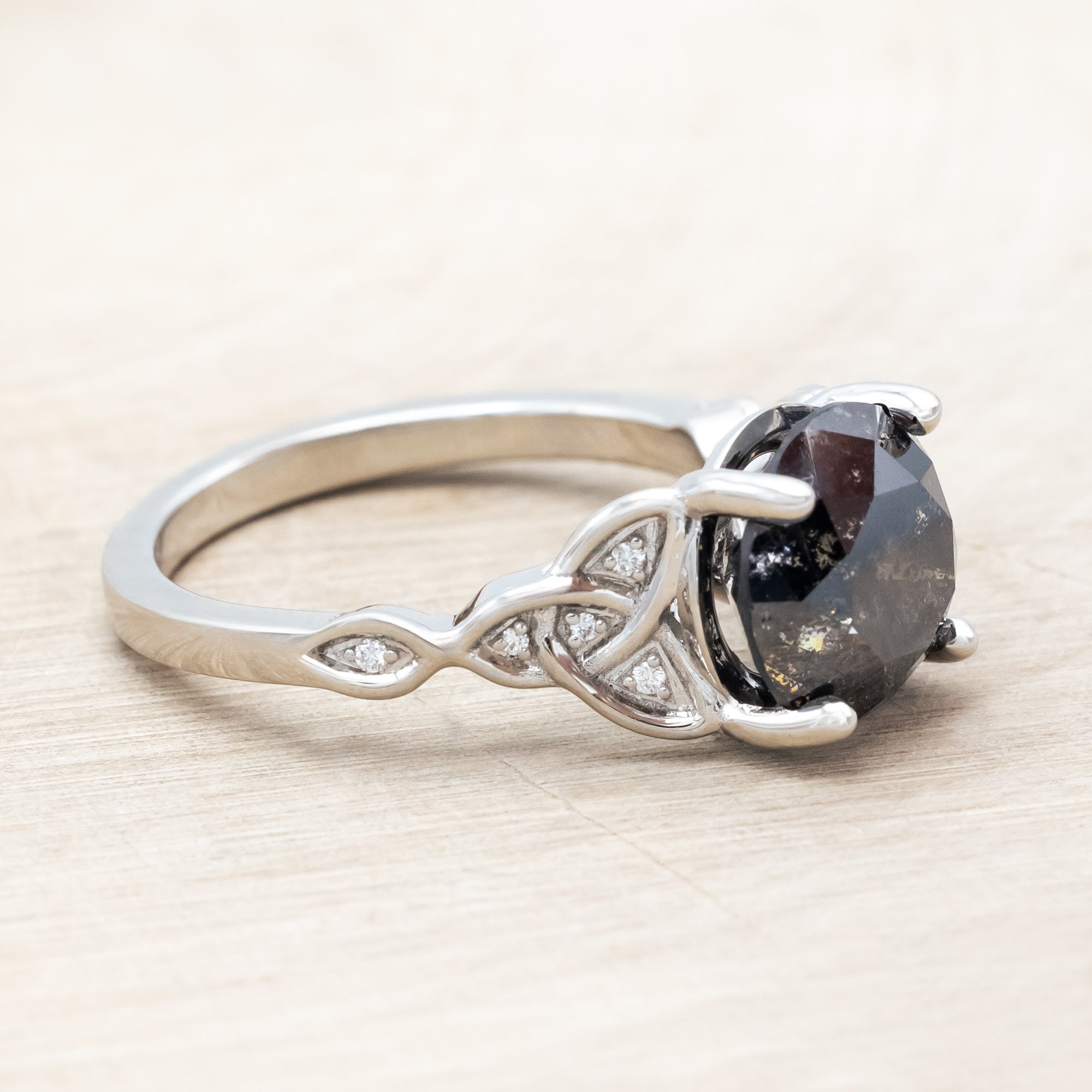 14K white gold ring with a salt & pepper diamond on a wooden surface