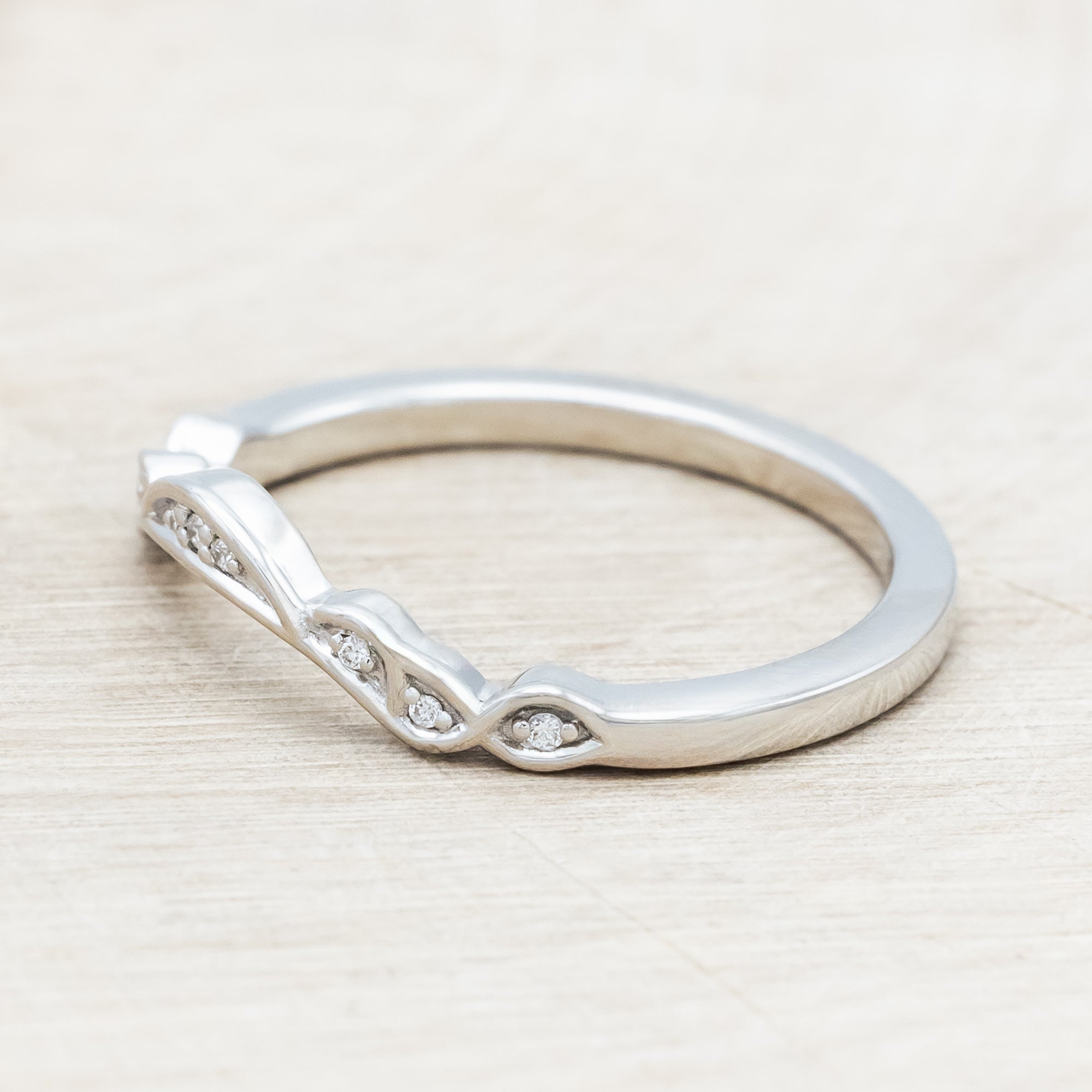 14K white gold ring with diamond accents on a wooden surface
