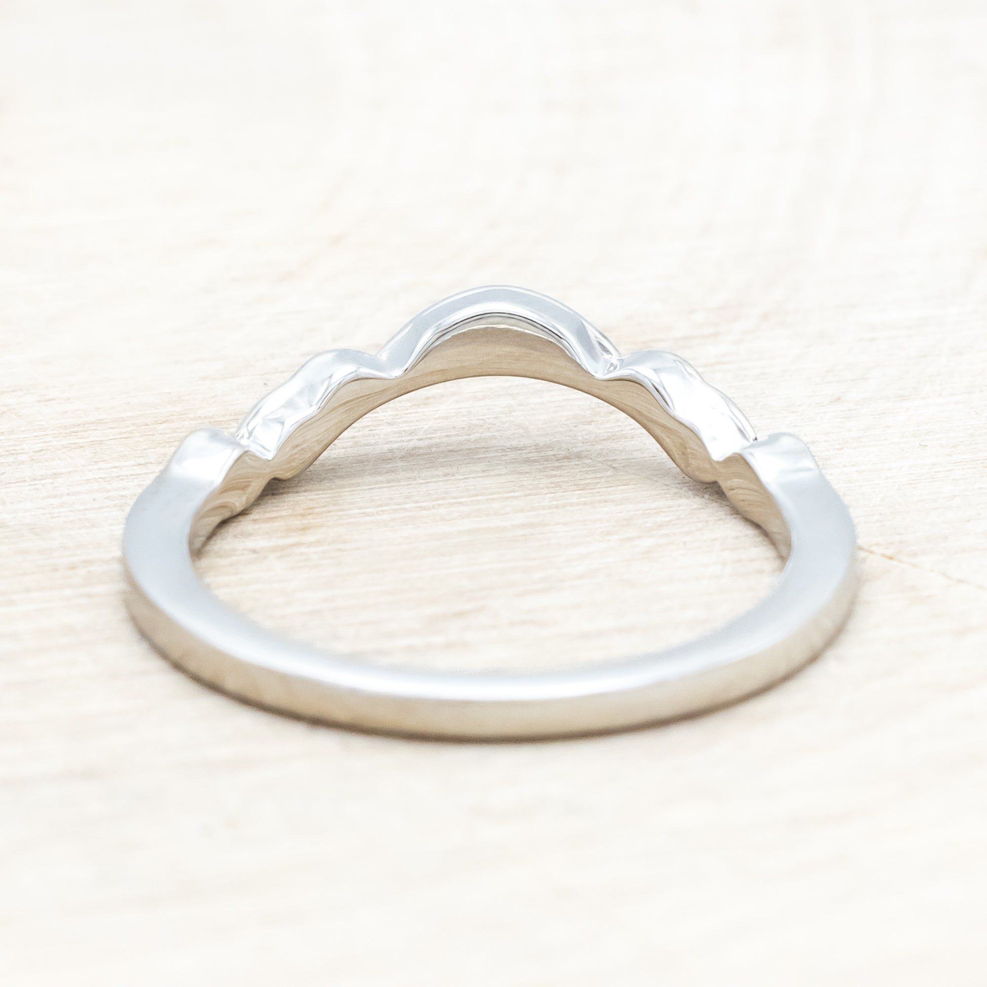 14K white gold ring with diamond accents on a wooden surface