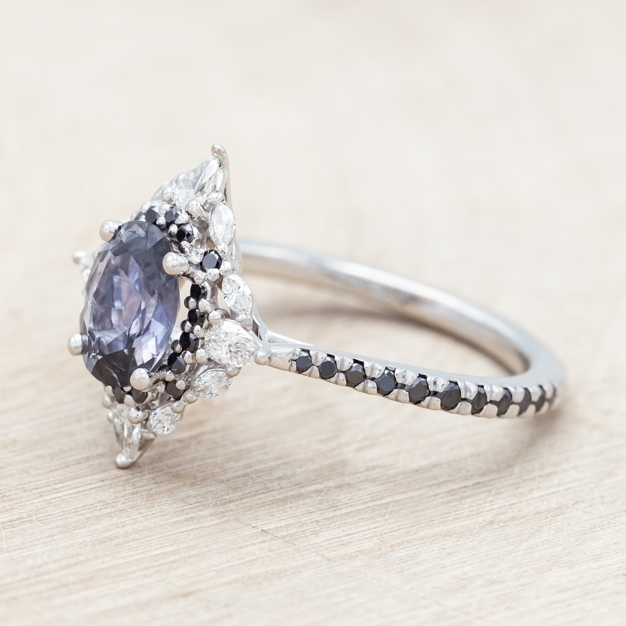 White gold ring with a blue sapphire and diamond accents on a beige background