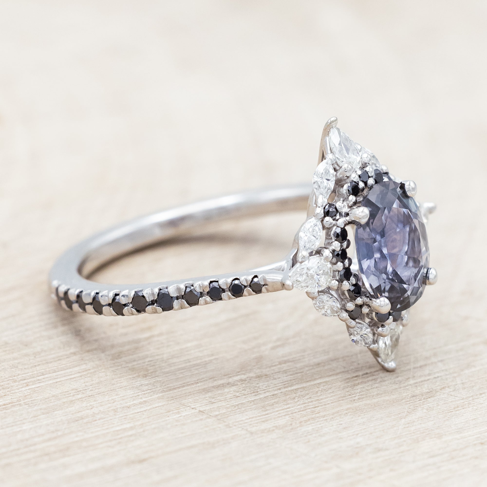 White gold ring with a blue sapphire and diamond accents on a beige background