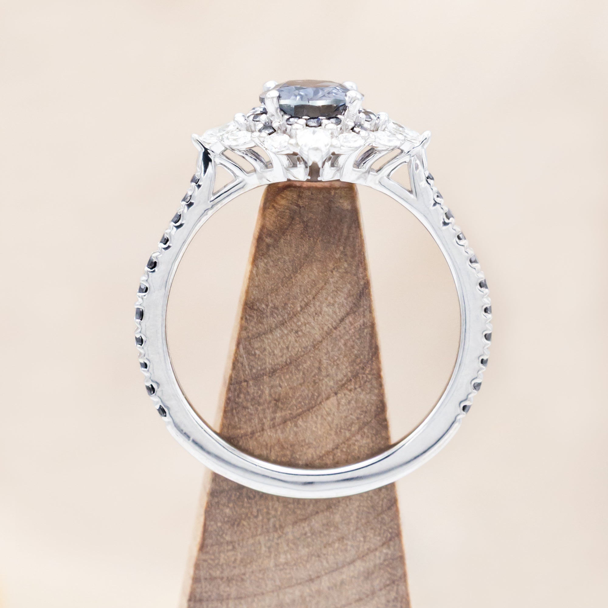 White gold ring with sapphire and diamond accents on a beige background