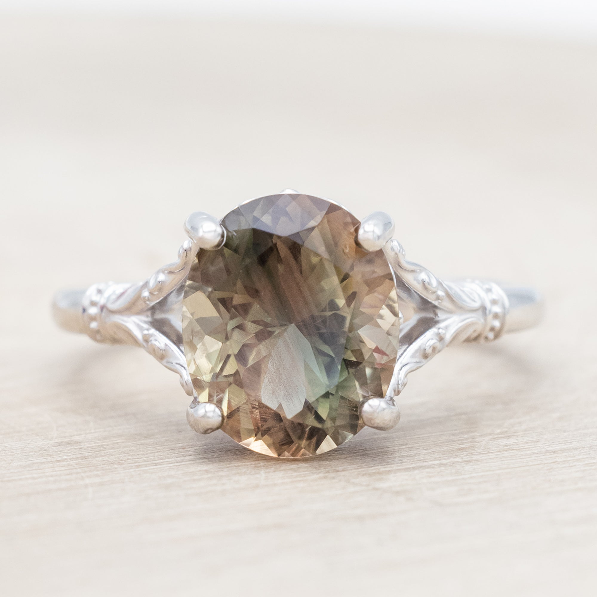 White gold ring with a sunstone on a wooden surface