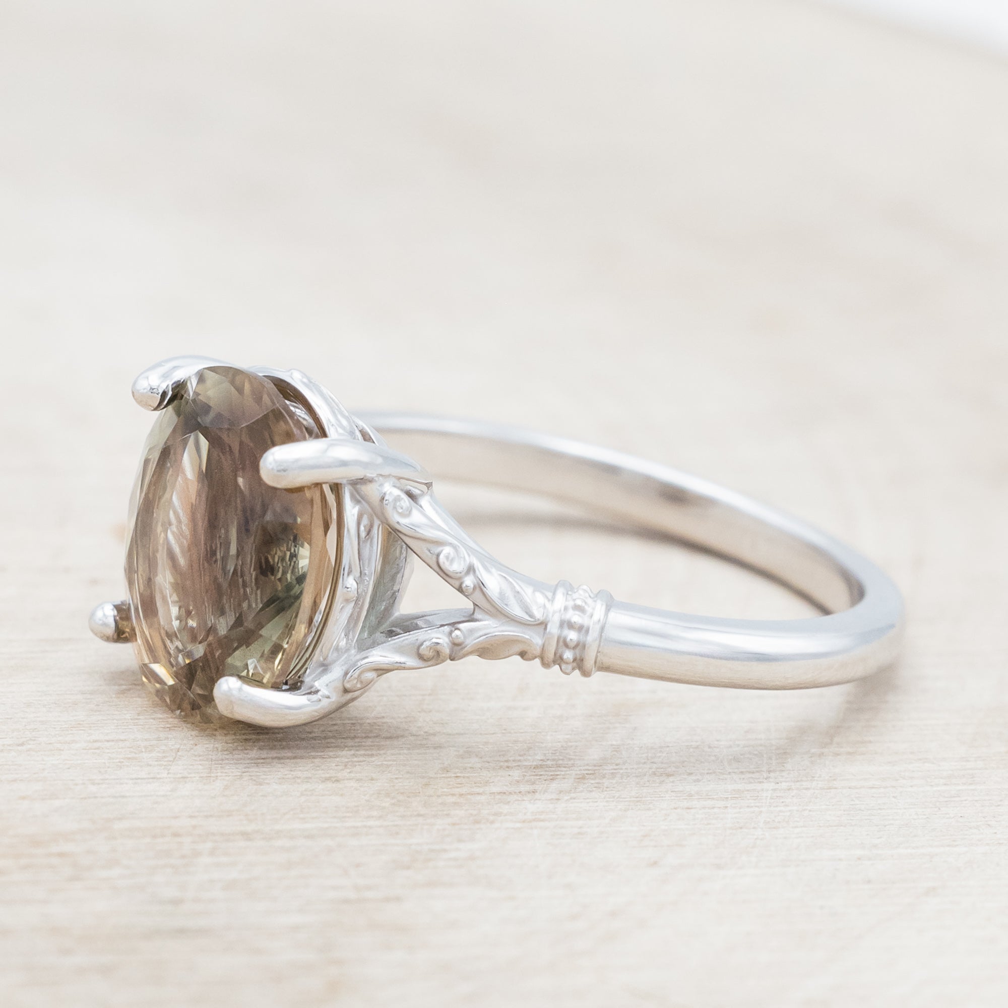 White gold ring with a sunstone on a wooden surface